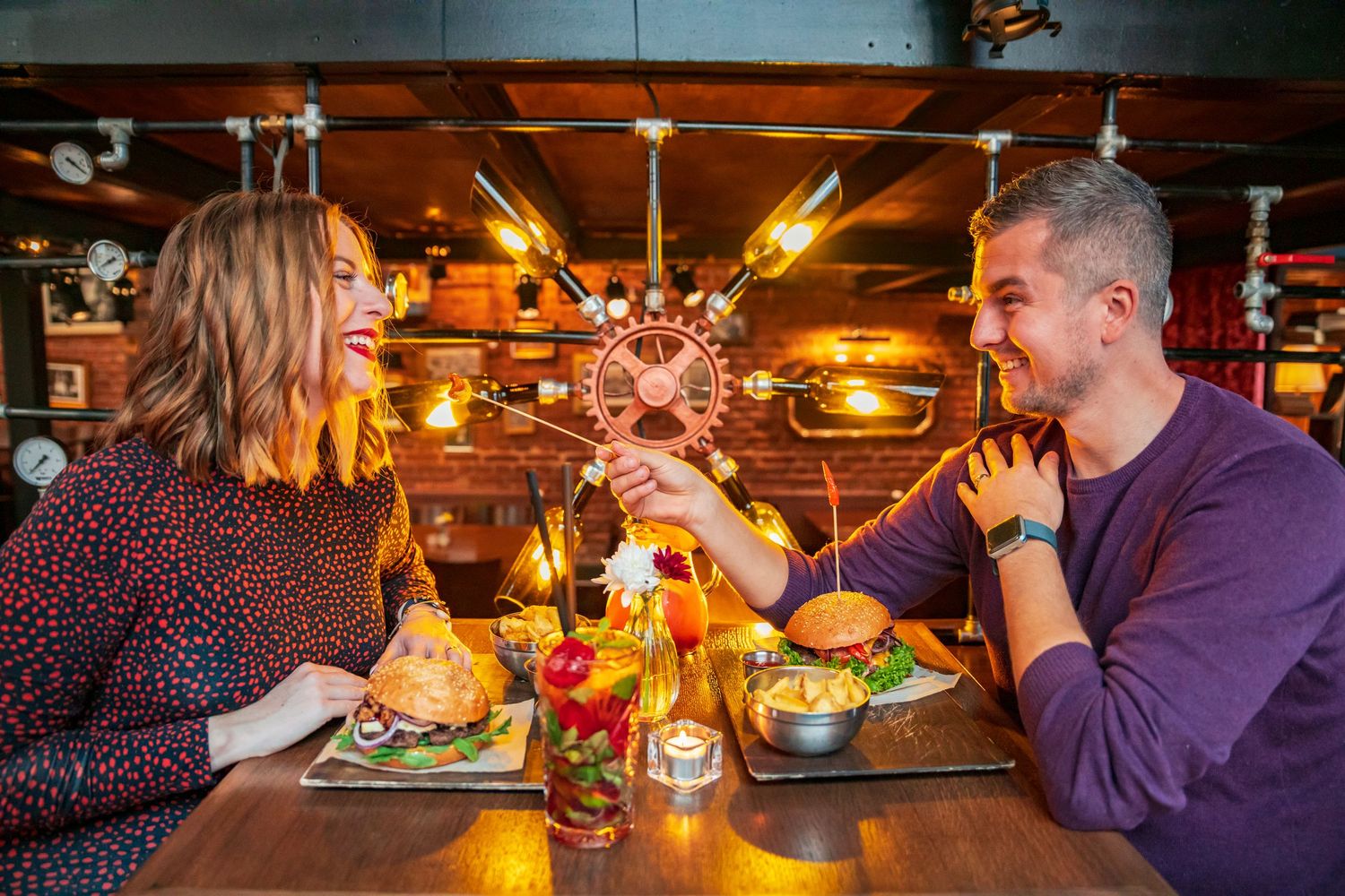 Restaurant scene showing diners engaged in conversation across a candlelit table.