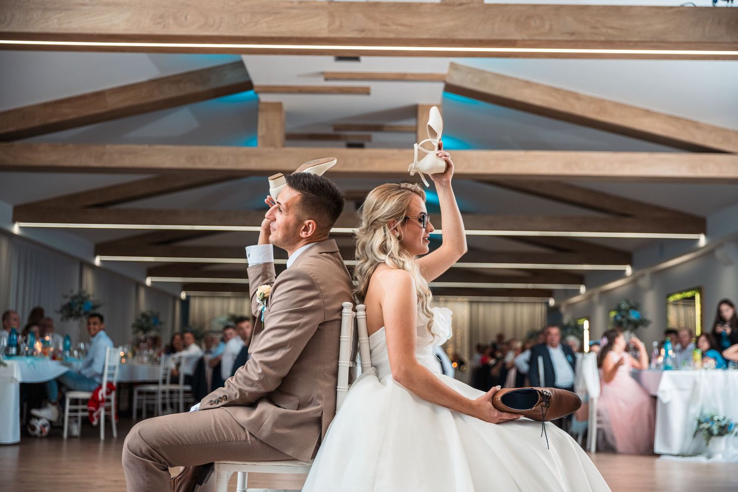 Wedding reception first dance with dramatic lighting and wooden beam ceiling details.