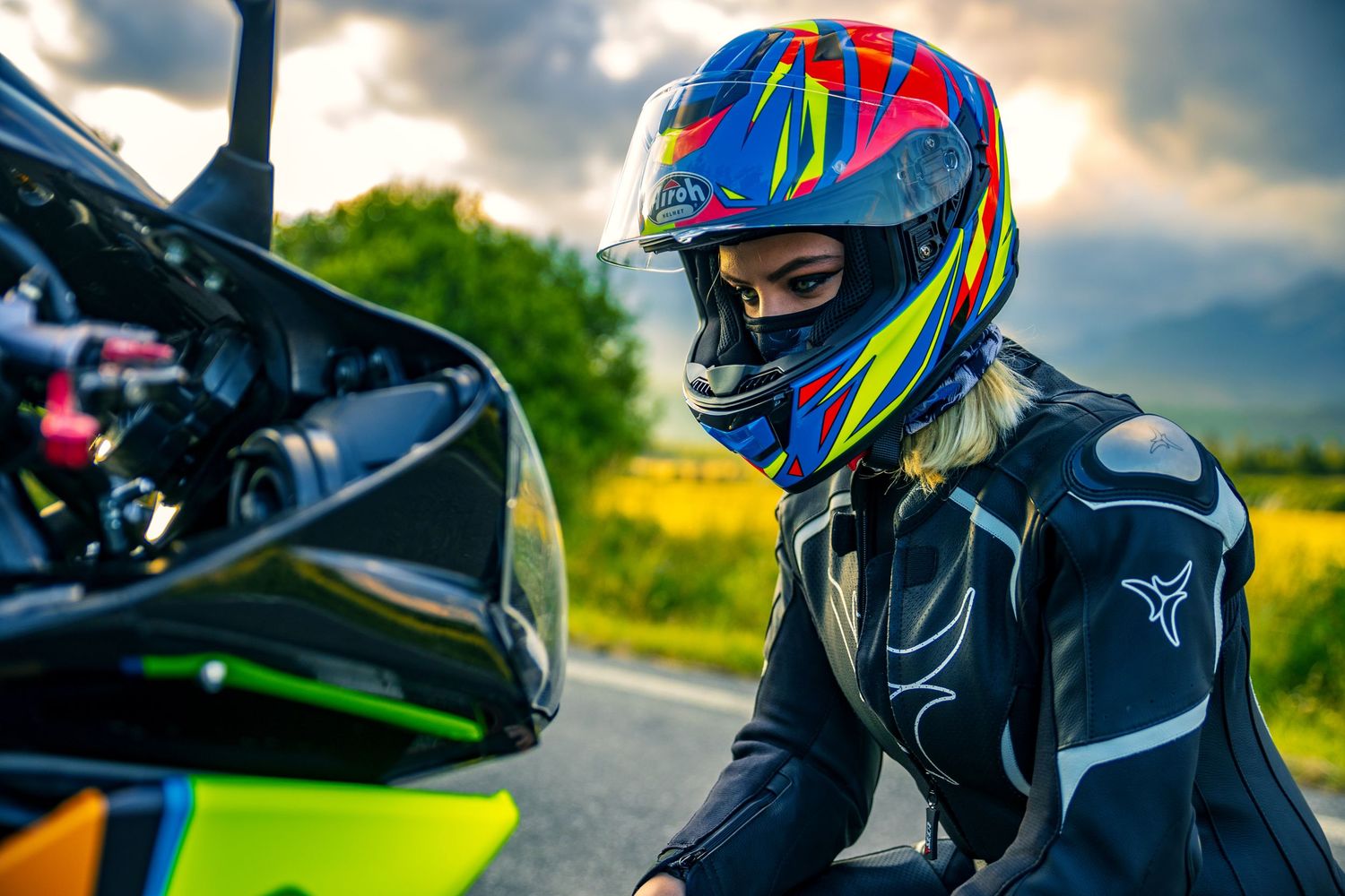 Motorcyclist in colorful helmet and gear riding sport bike during golden hour.