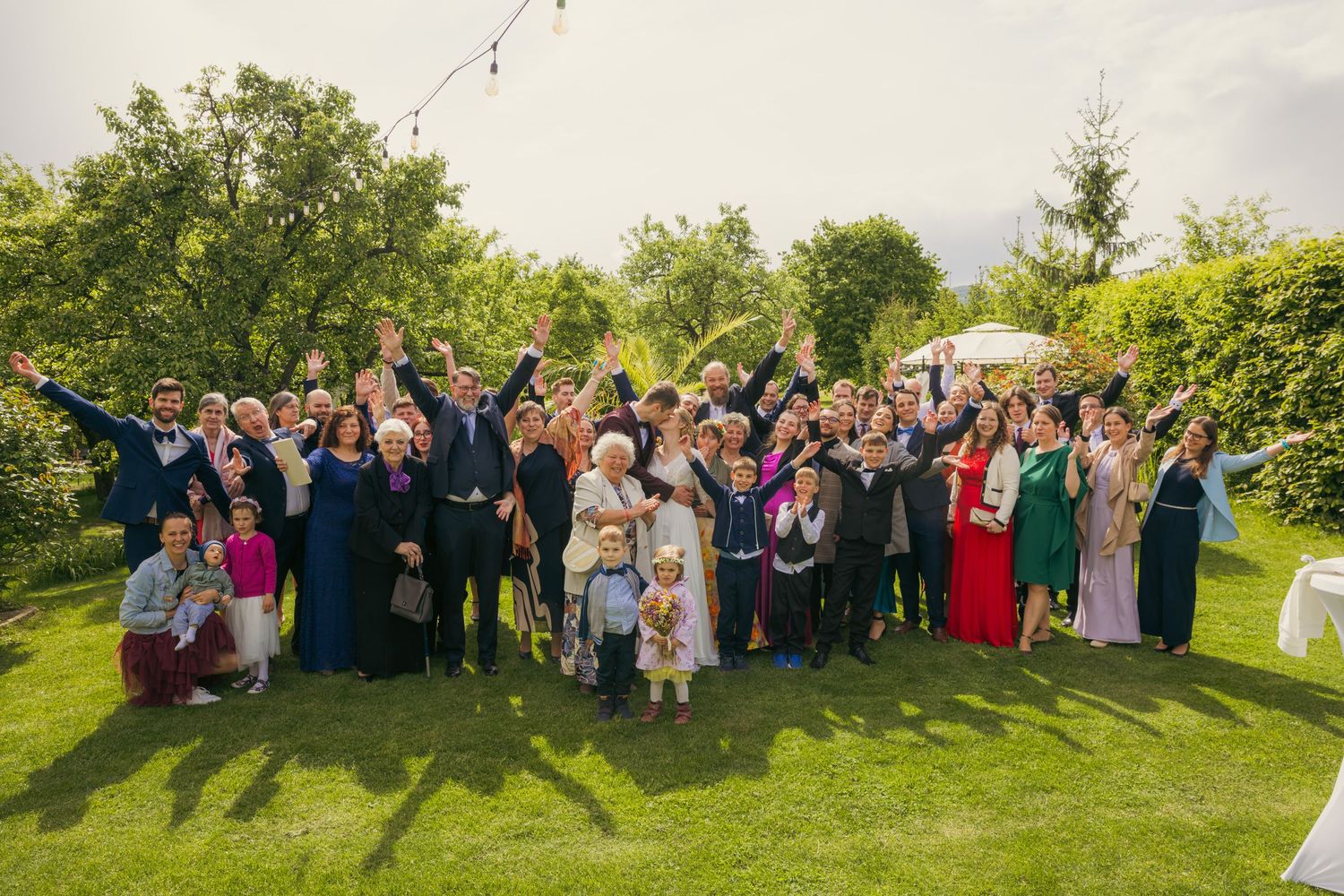 Large group wedding photo of guests gathered outdoors on a sunny day.