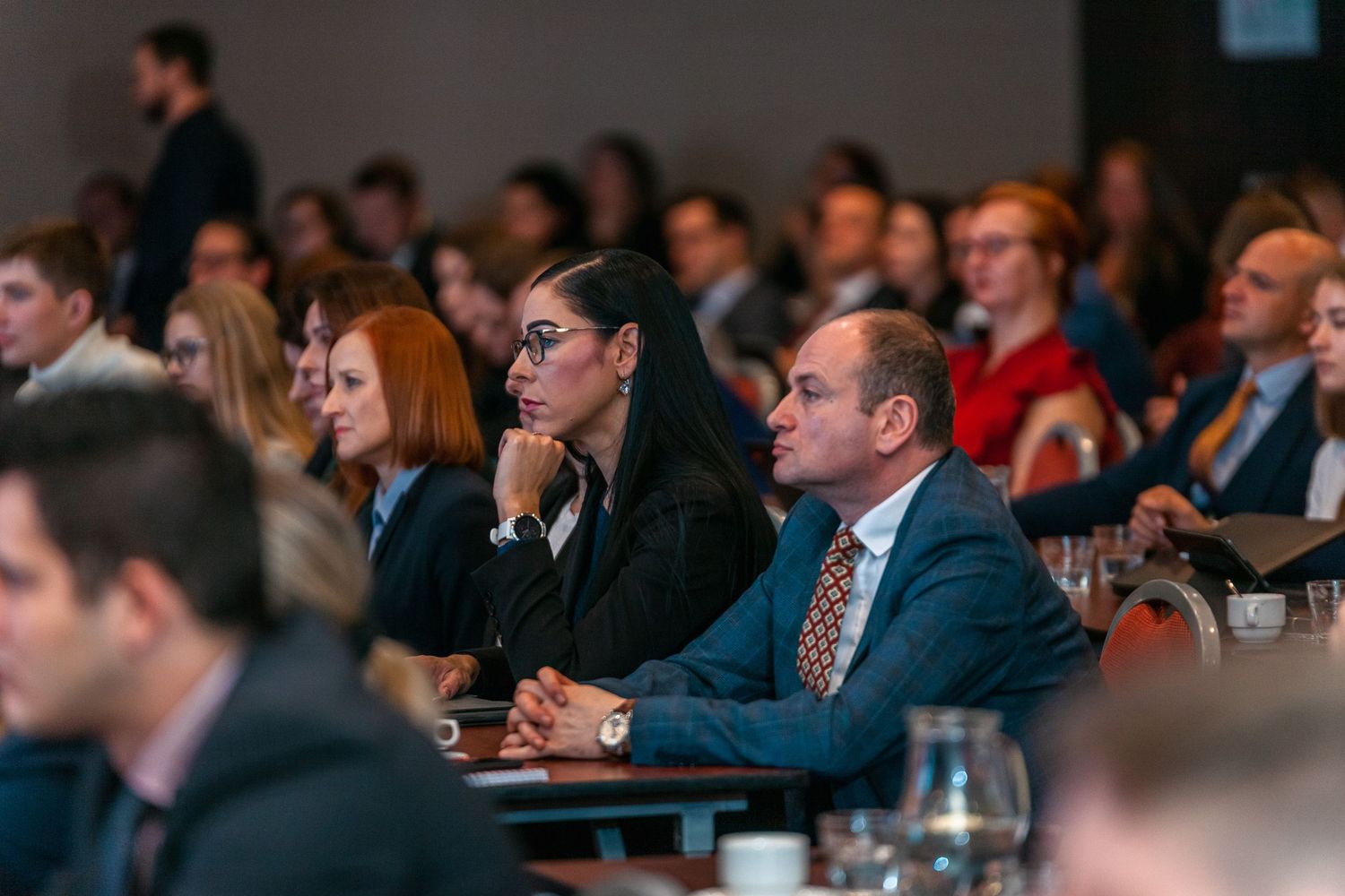 Audience members attentively listening during business conference presentation.