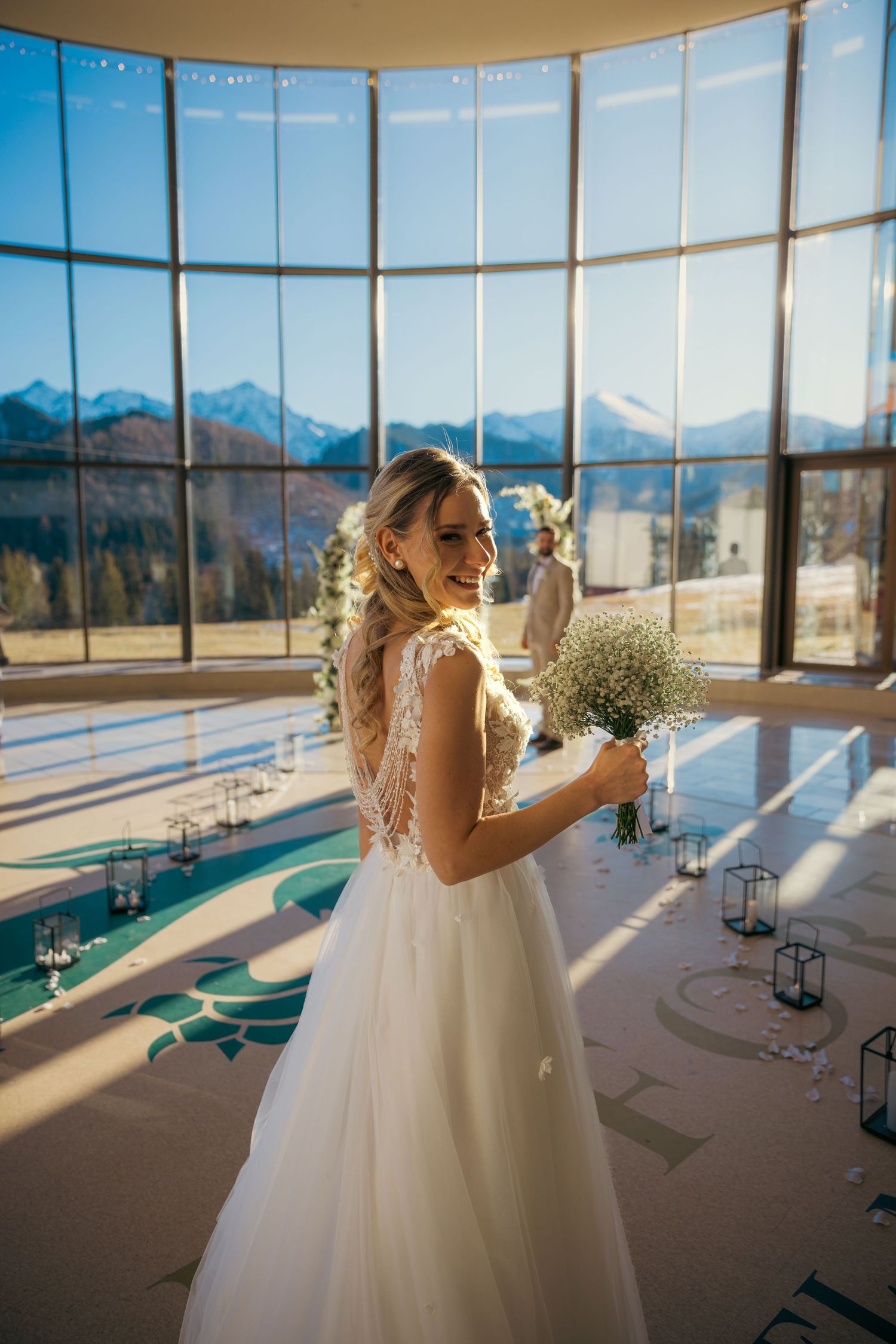 Sunlit wedding venue with panoramic mountain views and elegant white decor details.
