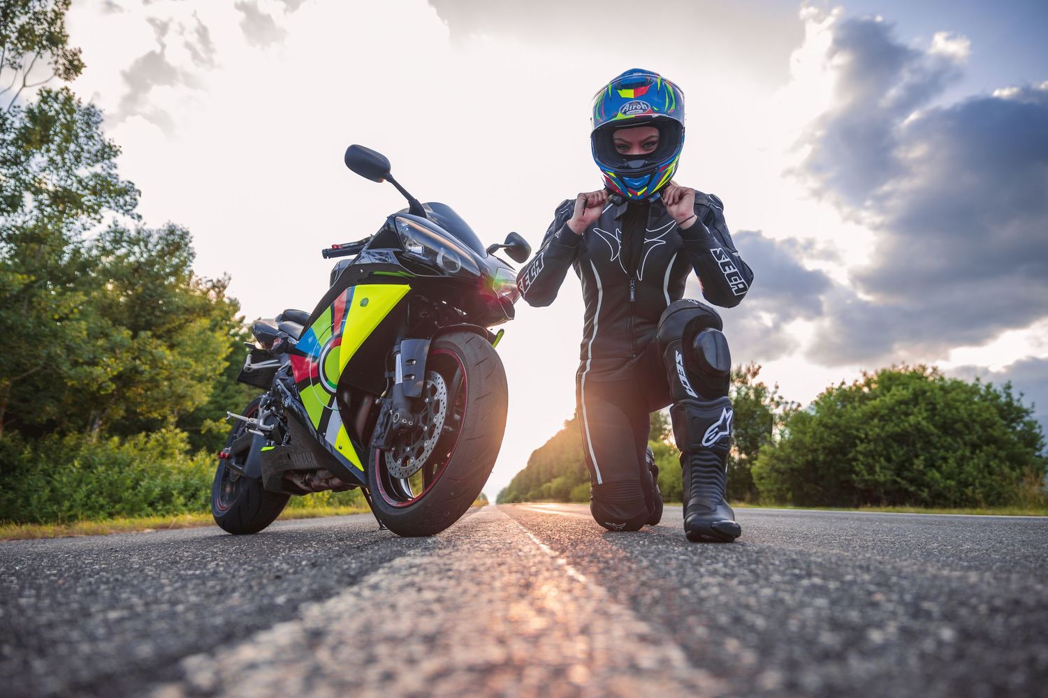 Low angle shots of motorcycle and rider against dramatic cloudy sky at sunset.