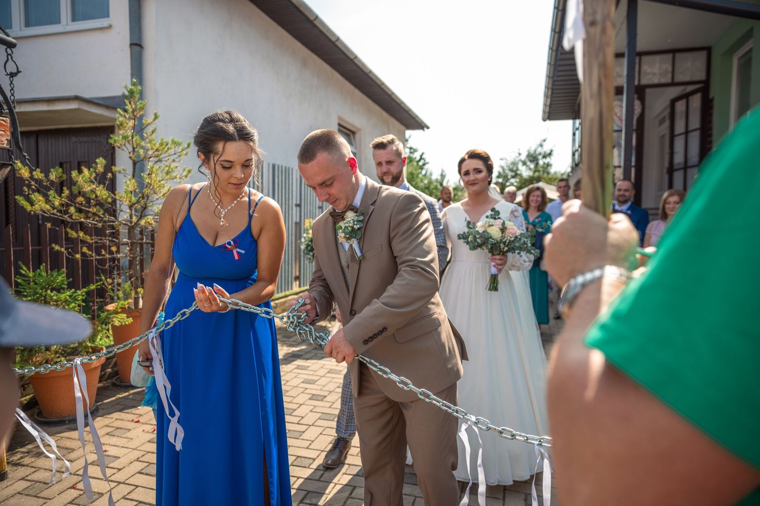 Wedding guests in colorful attire gather outdoors for celebration photos.
