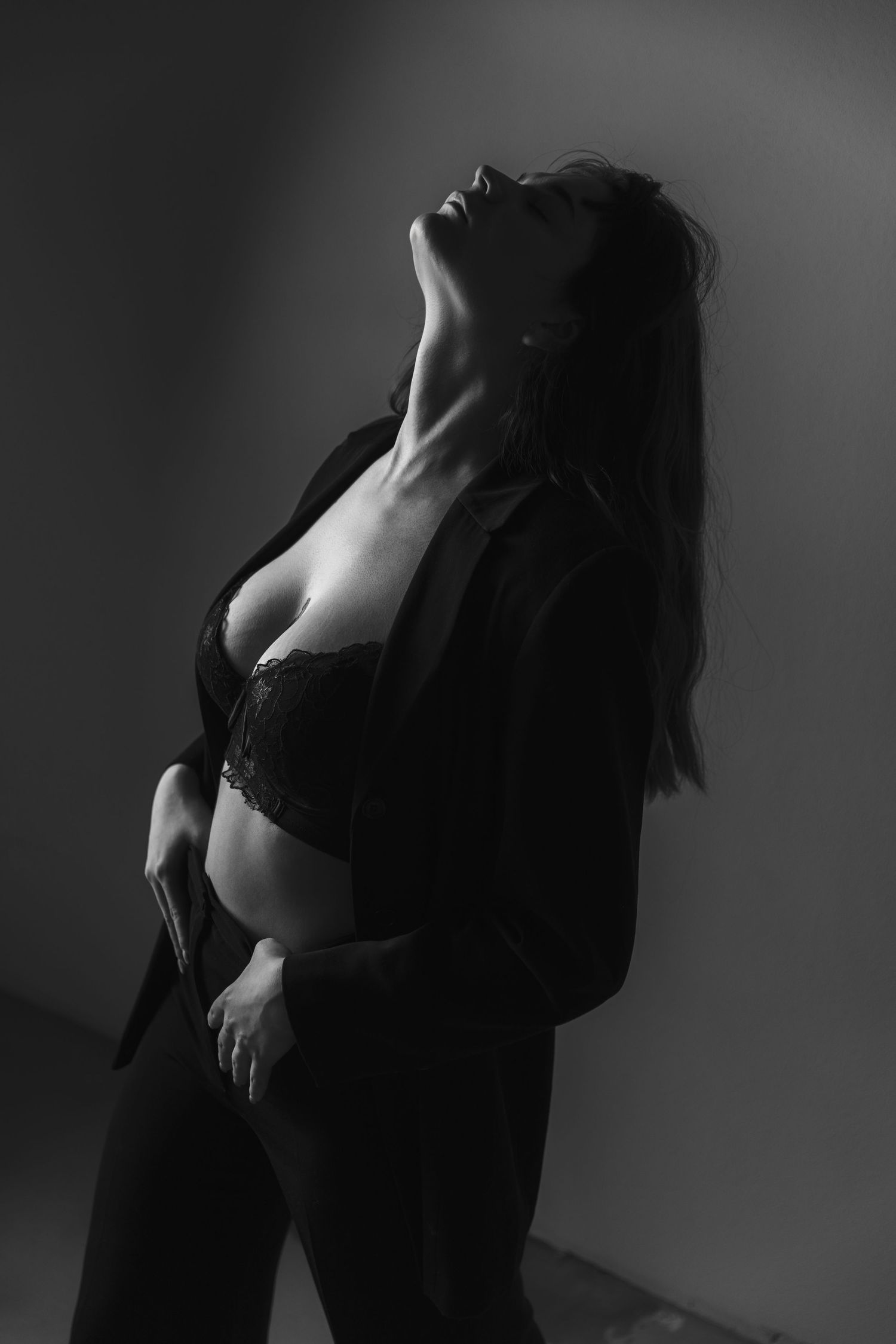 Artistic black and white boudoir photo with dramatic lighting and shadows.