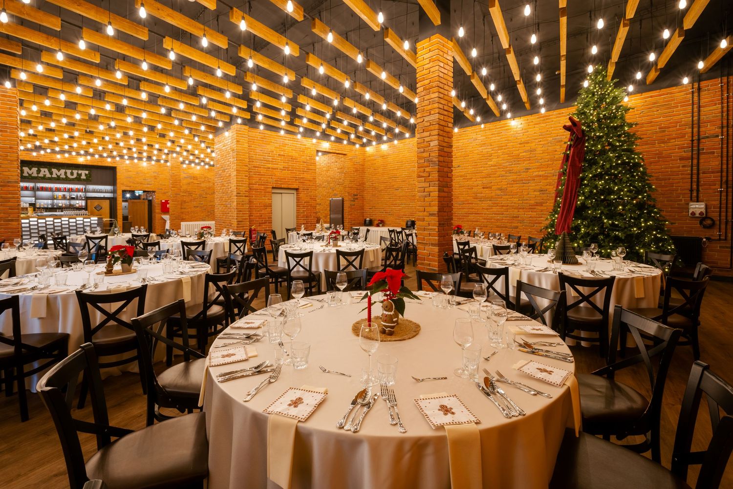 Elegant banquet hall with string lights and round tables set for a wedding reception.