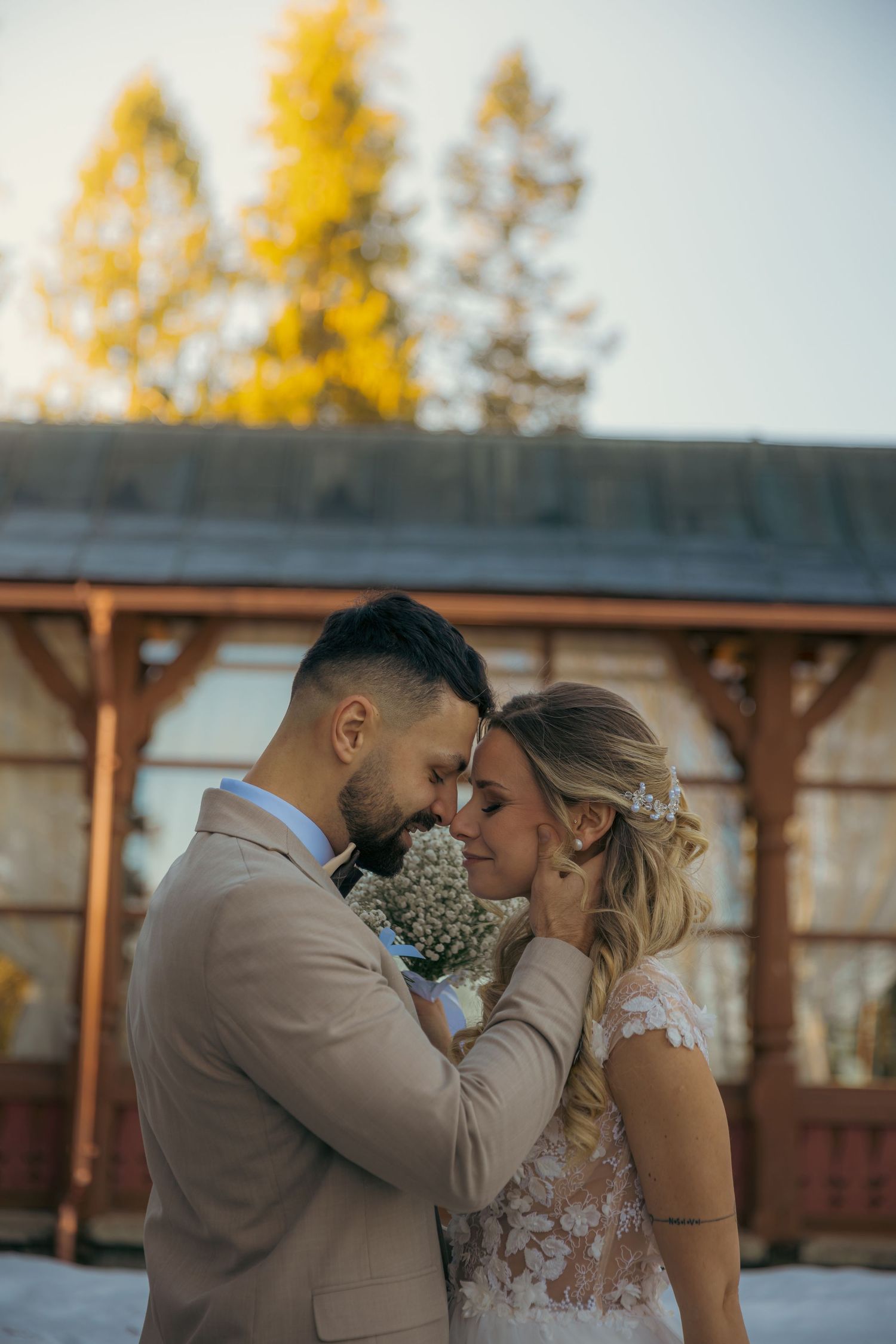 Romantic autumn wedding portrait with couple embracing against rustic wooden backdrop.