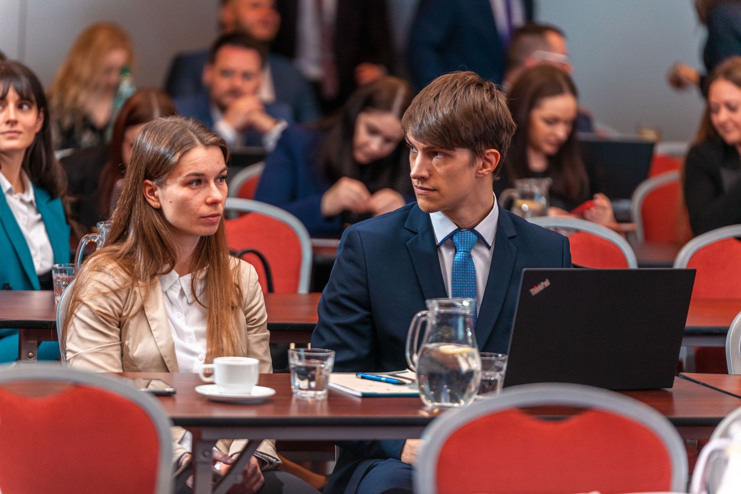 Conference attendees working with laptop at table during business event.
