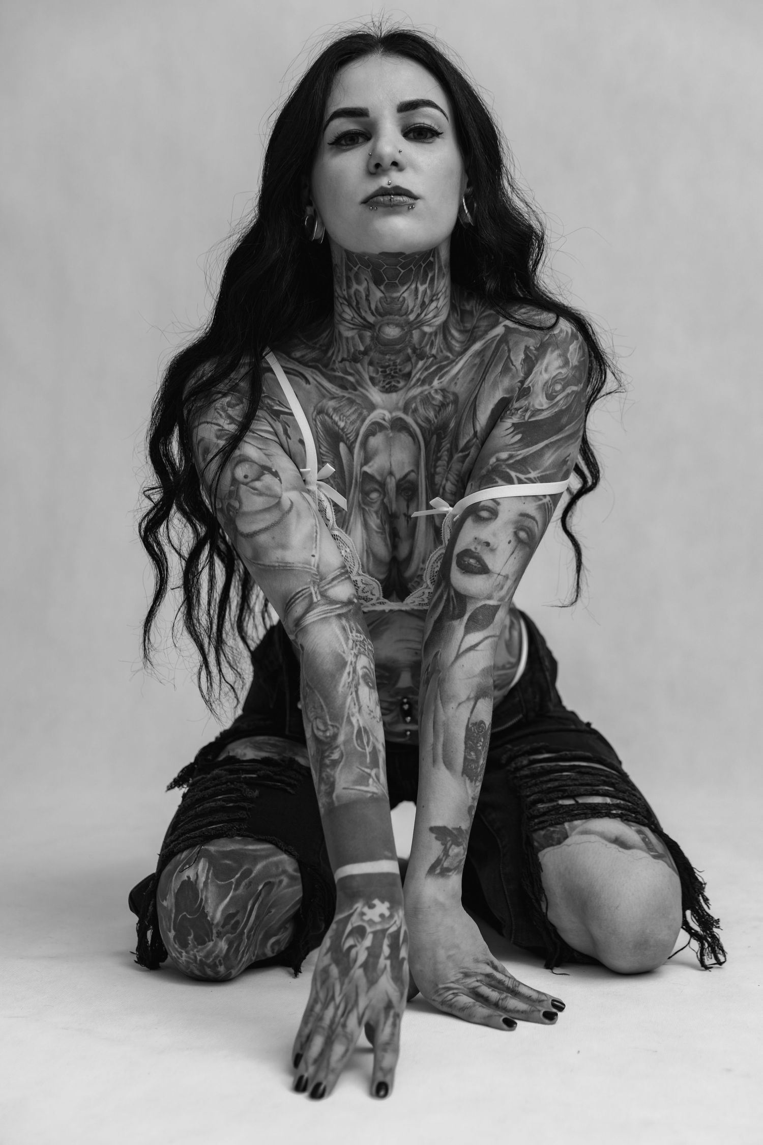Black and white artistic portrait showcasing intricate full-body tattoo artwork against white background.