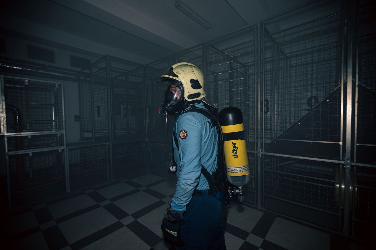 Dark industrial corridor with emergency lighting and safety equipment visible.