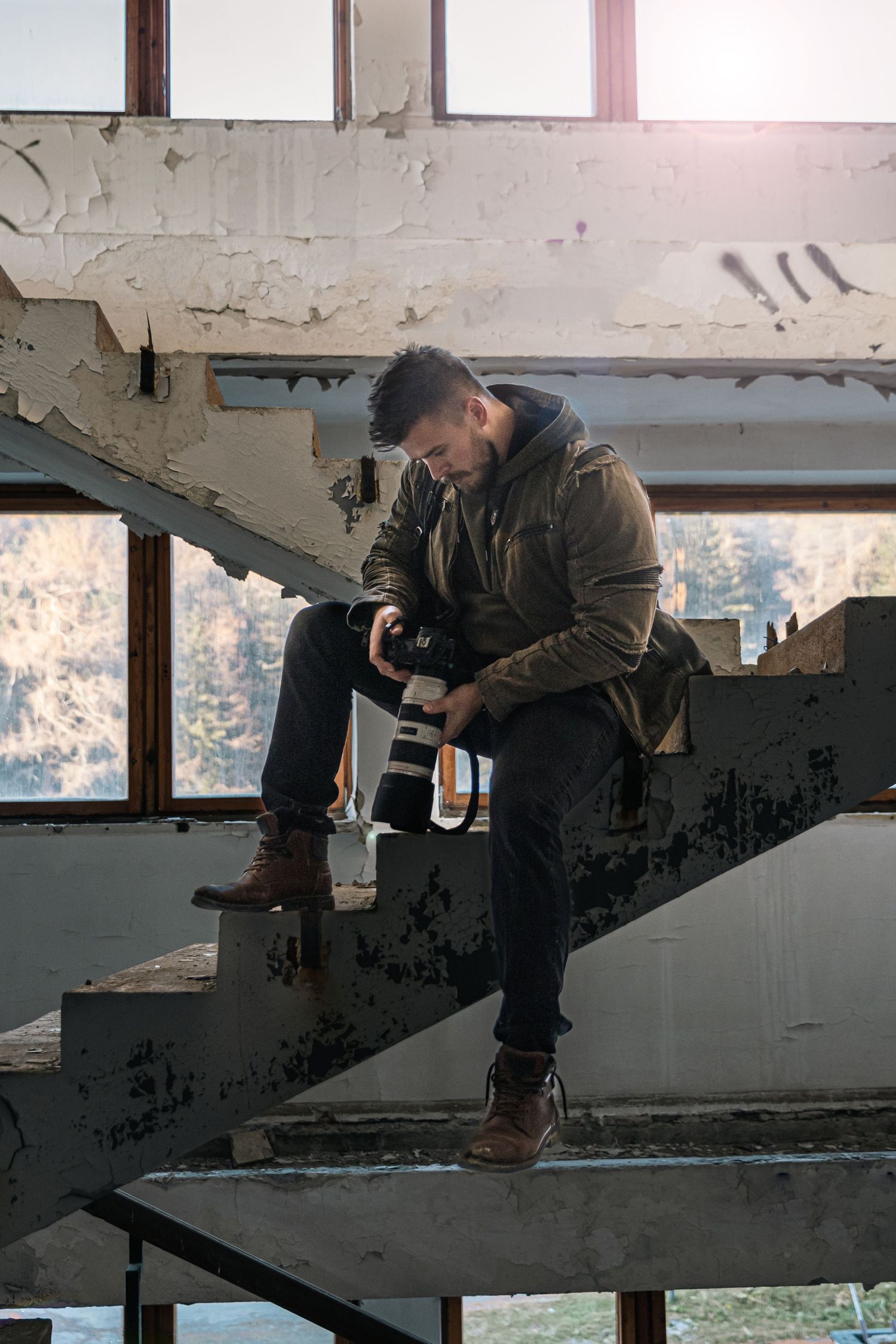 Photographer works in abandoned building with peeling walls and natural window light.