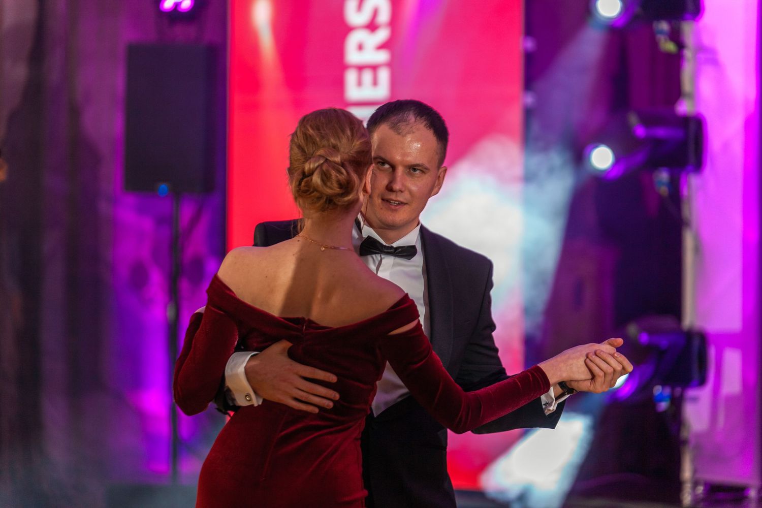 Elegant ballroom event with dramatic purple and red lighting effects creating an atmospheric ambiance.