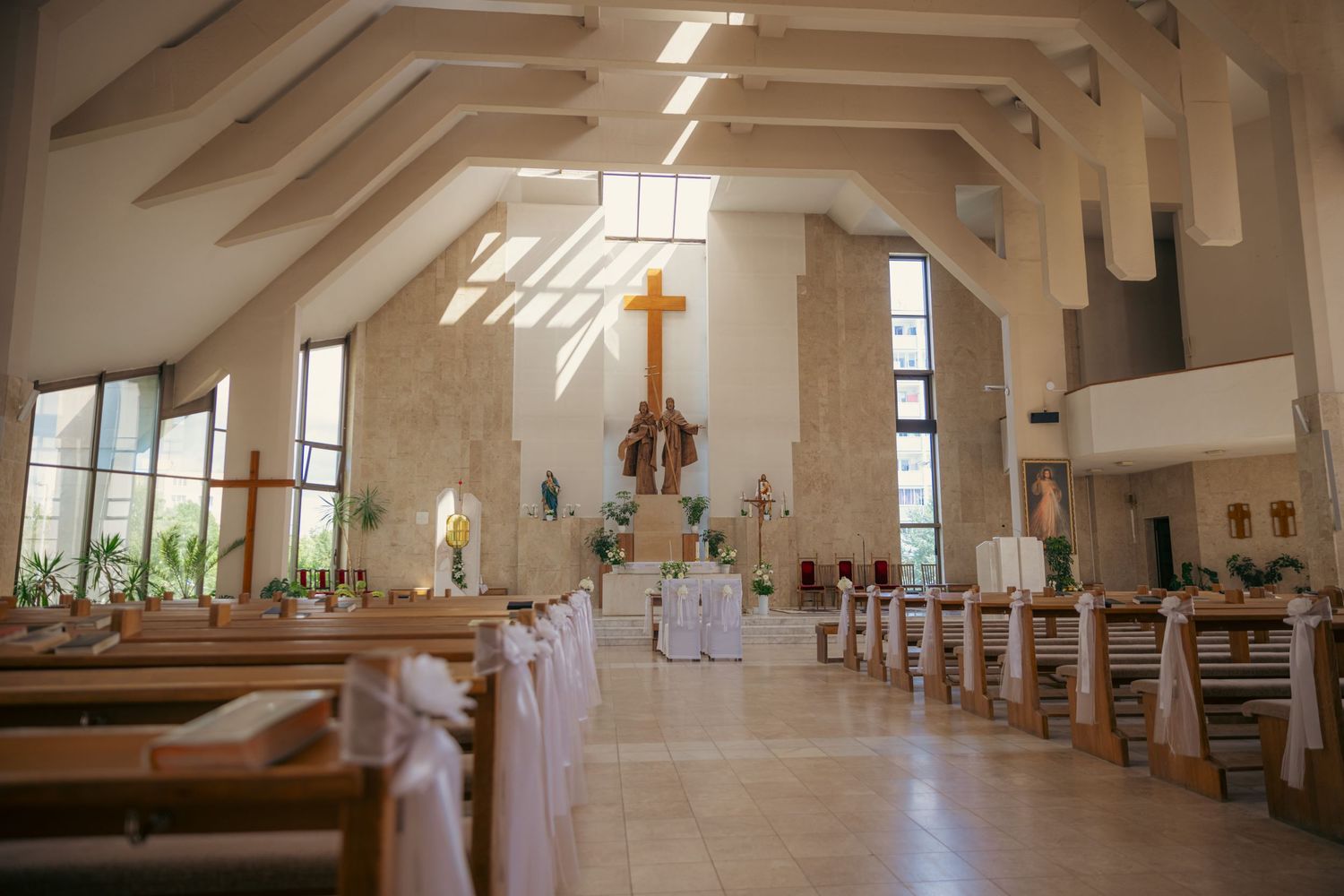 Modern church interior with white walls, exposed beams, and natural light streaming through windows.