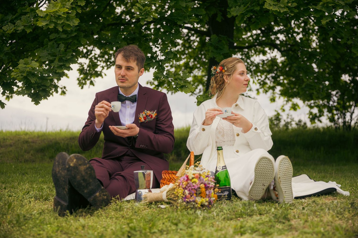 Picnic scene with people relaxing on grass during summer day.