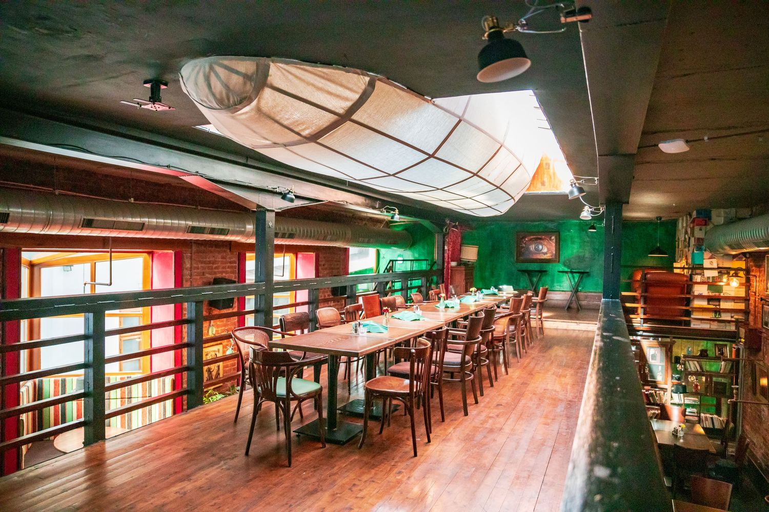 Long view of an empty restaurant interior with green accents and wooden furniture.