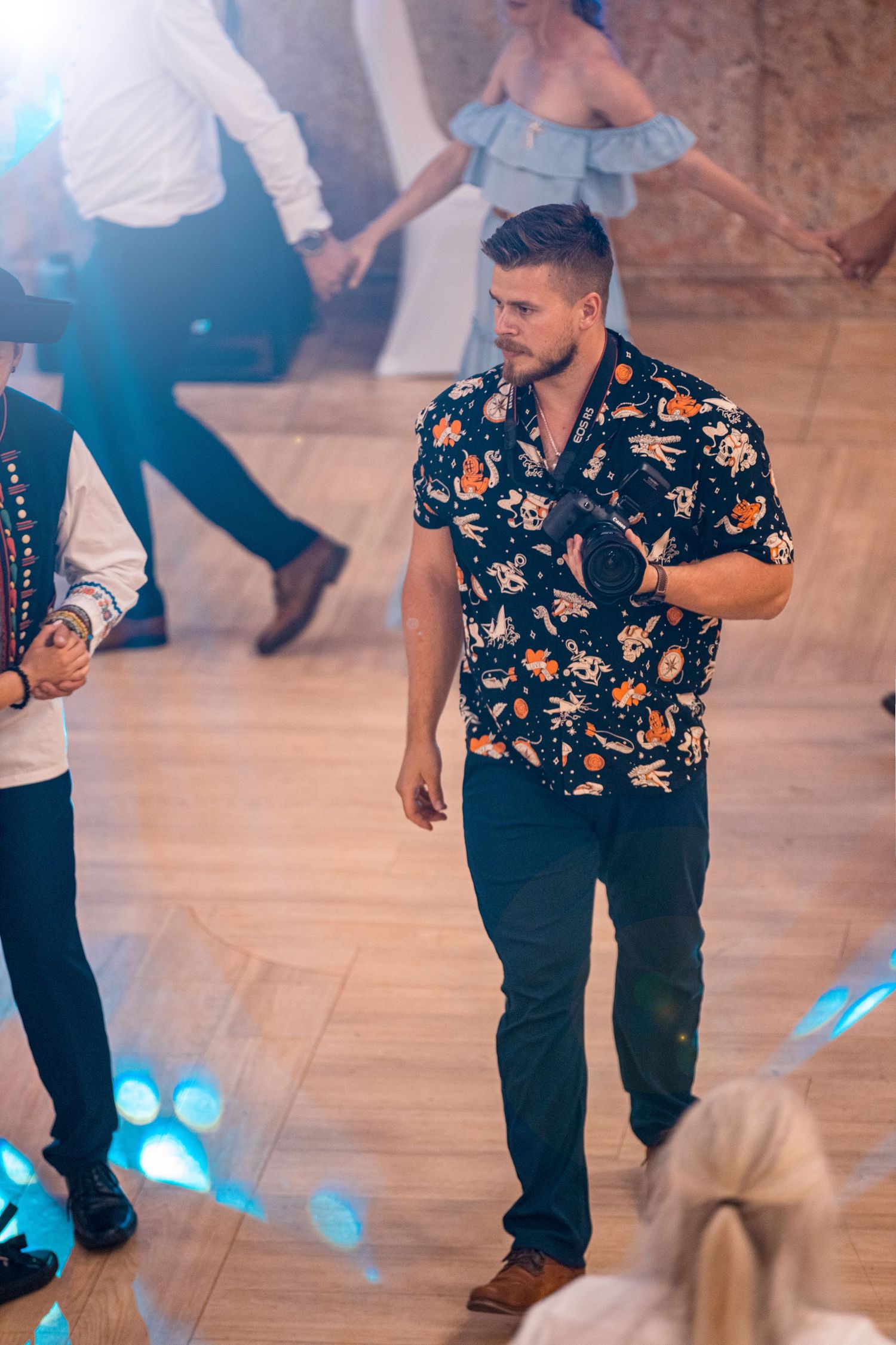 Dancing scene on wooden floor with colorful lighting and floral shirt in focus.