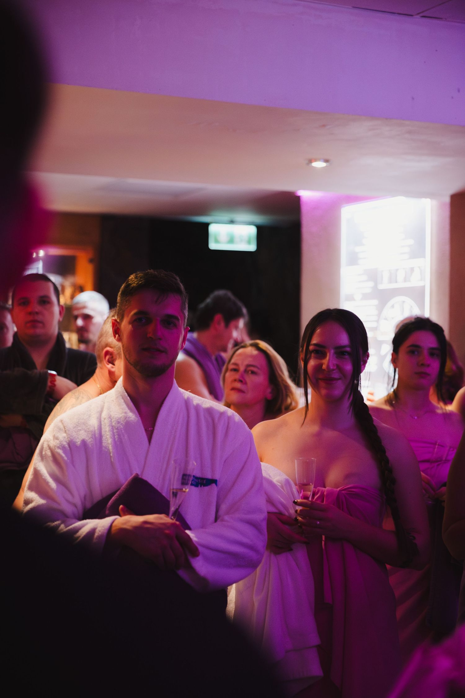 Group of people in formal attire gathered under purple lighting at an event.