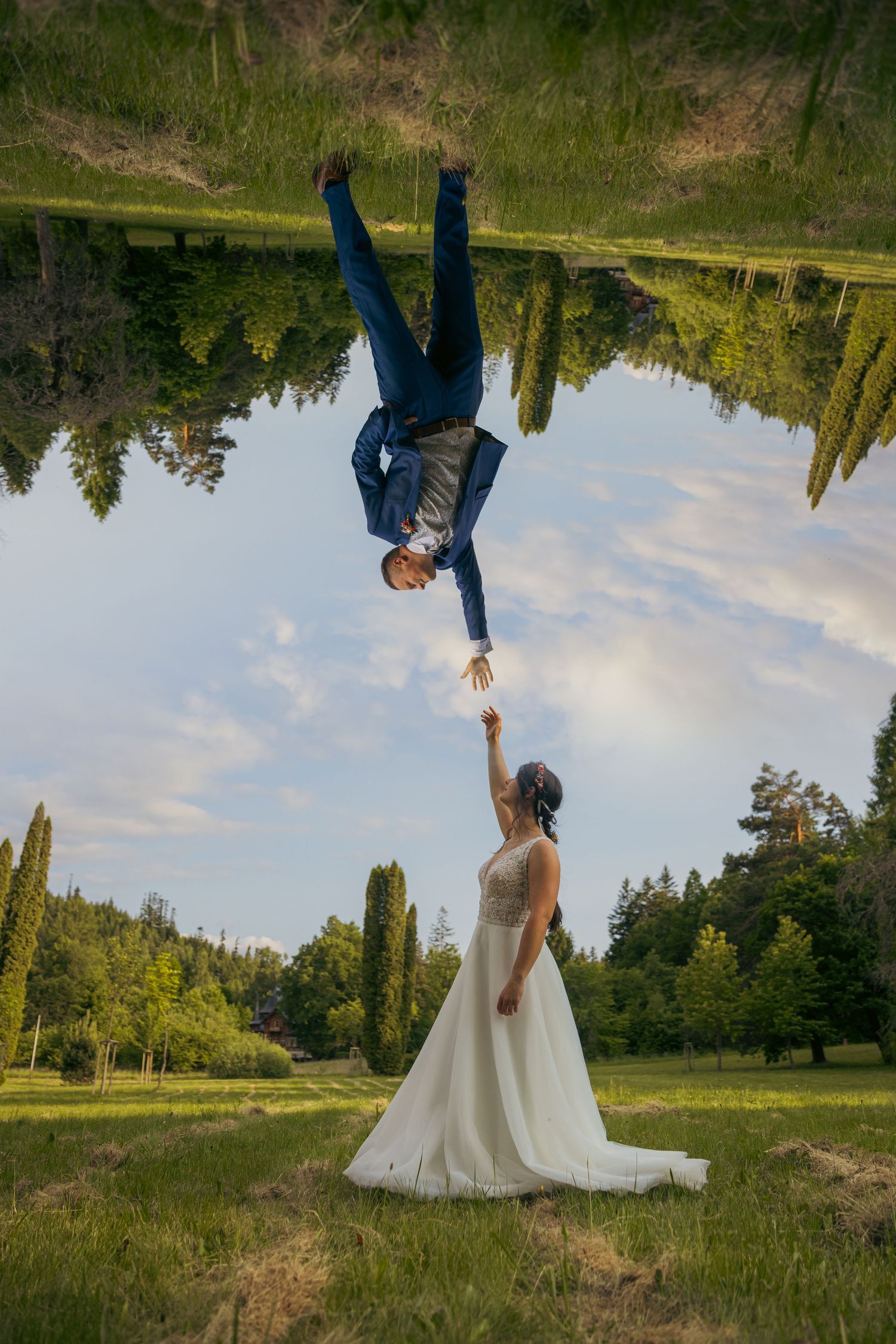Creative upside-down wedding photo composition in a sunny meadow with mountain backdrop.