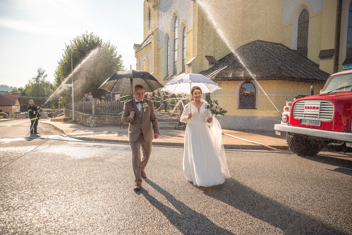 Wedding party members walk and pose for candid shots on a sunny paved pathway.