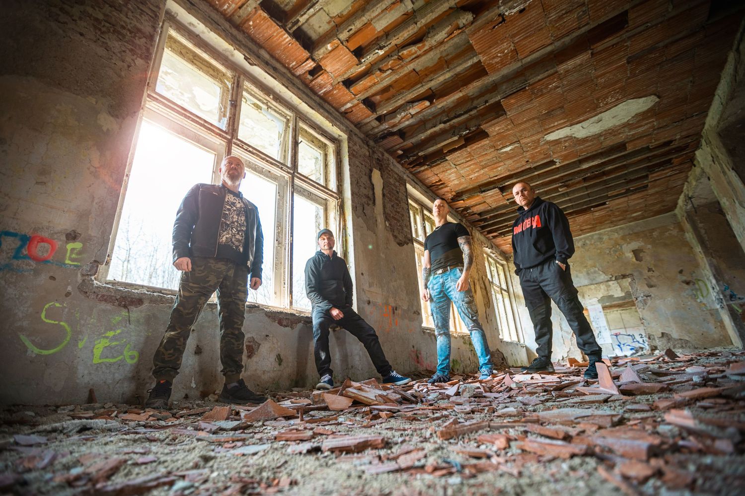 Wide angle view of a deteriorating abandoned building interior with exposed beams.