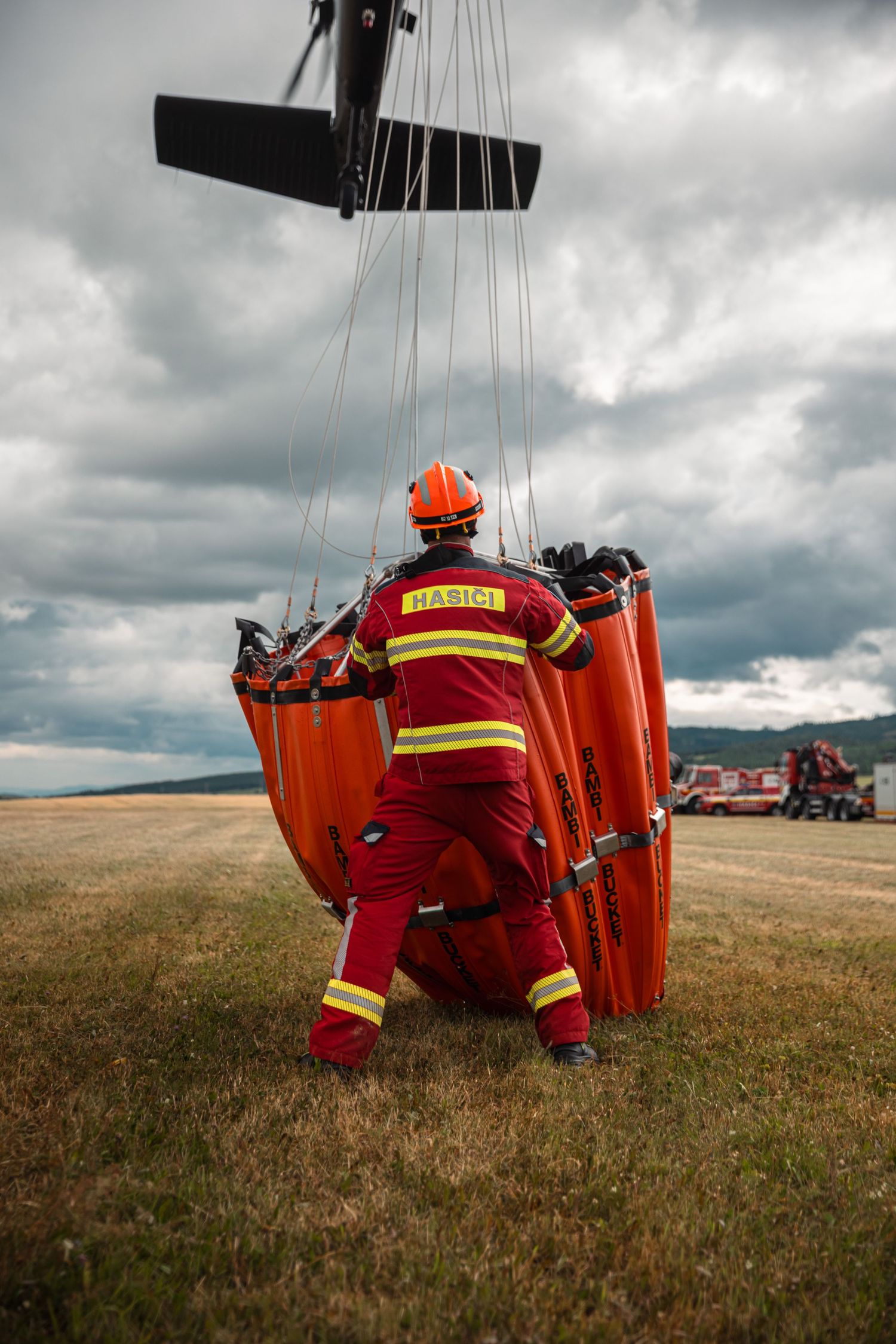 Emergency rescue equipment being airlifted by helicopter in an open field.