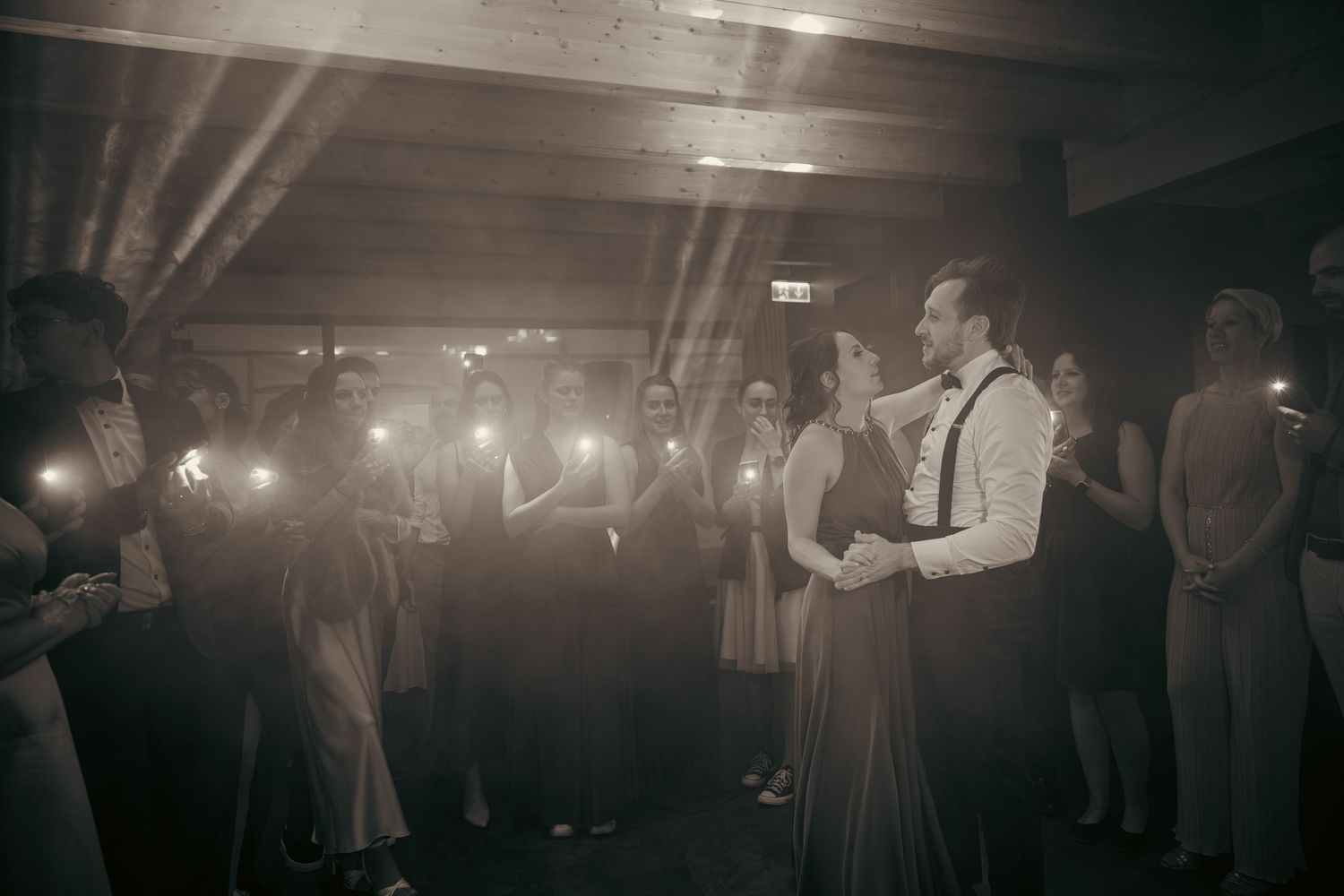 Silhouettes of wedding guests dancing at a dimly lit reception party.