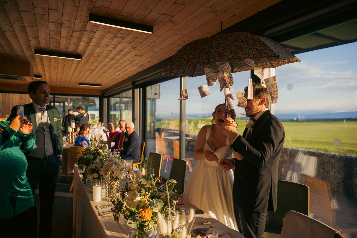 Wedding reception venue with wooden ceiling beams and hanging decorative lights creating a warm ambiance.