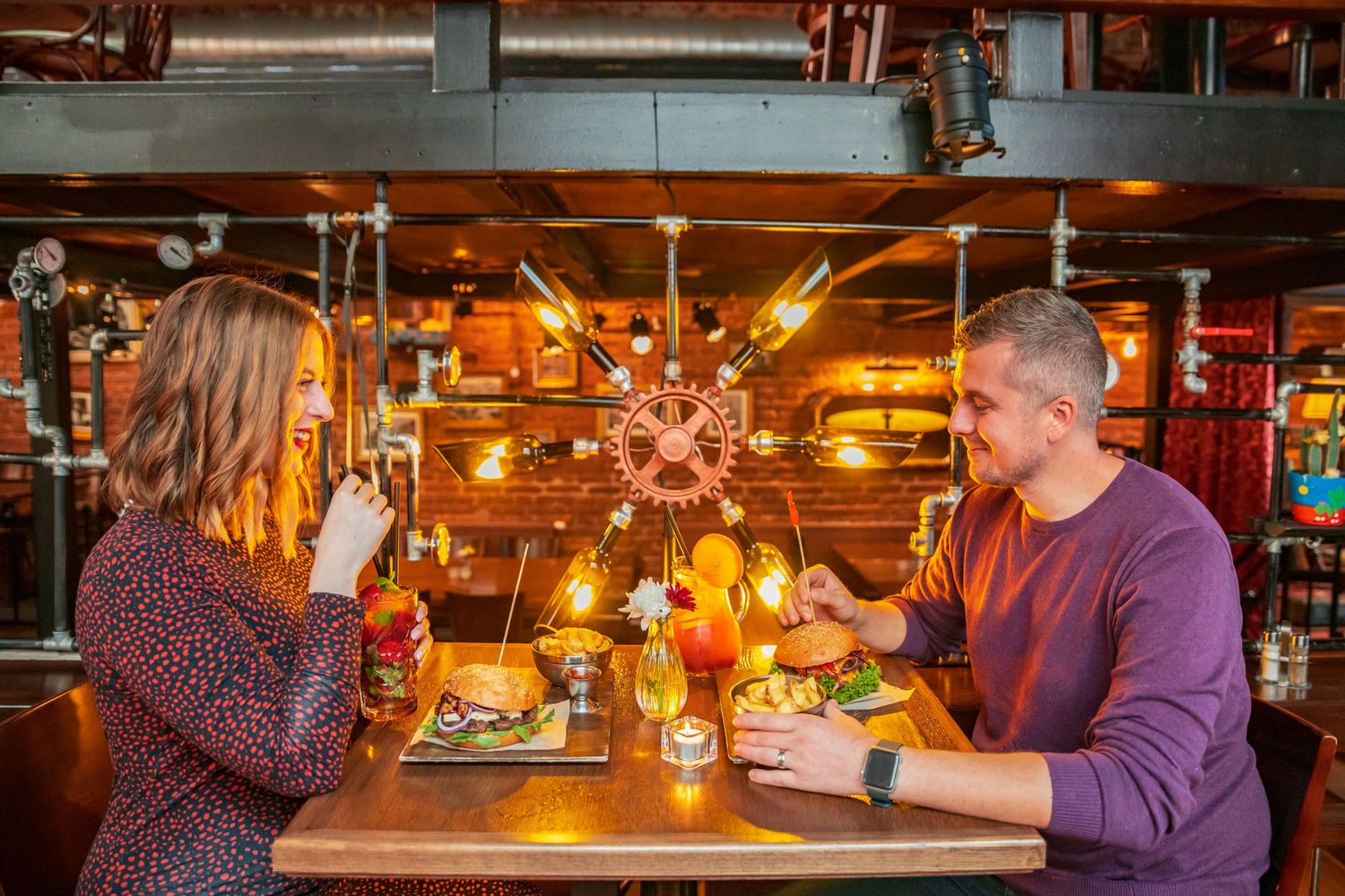 Diners enjoying a meal in a warmly lit restaurant with rustic decor and ambient lighting.