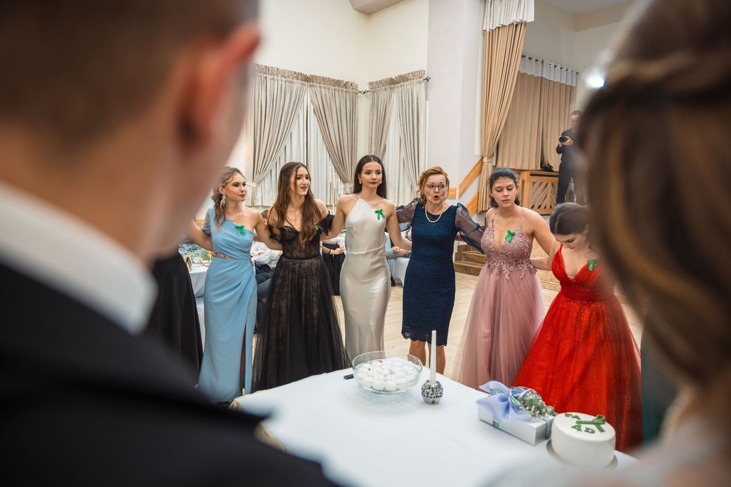 Event guests in formal attire celebrating and dancing in bright indoor venue.