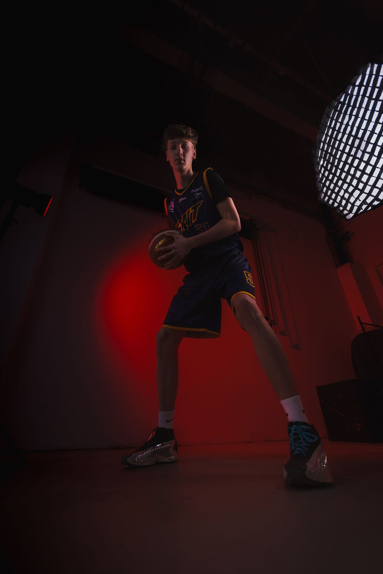 Basketball player in action pose with dramatic lighting and red background.