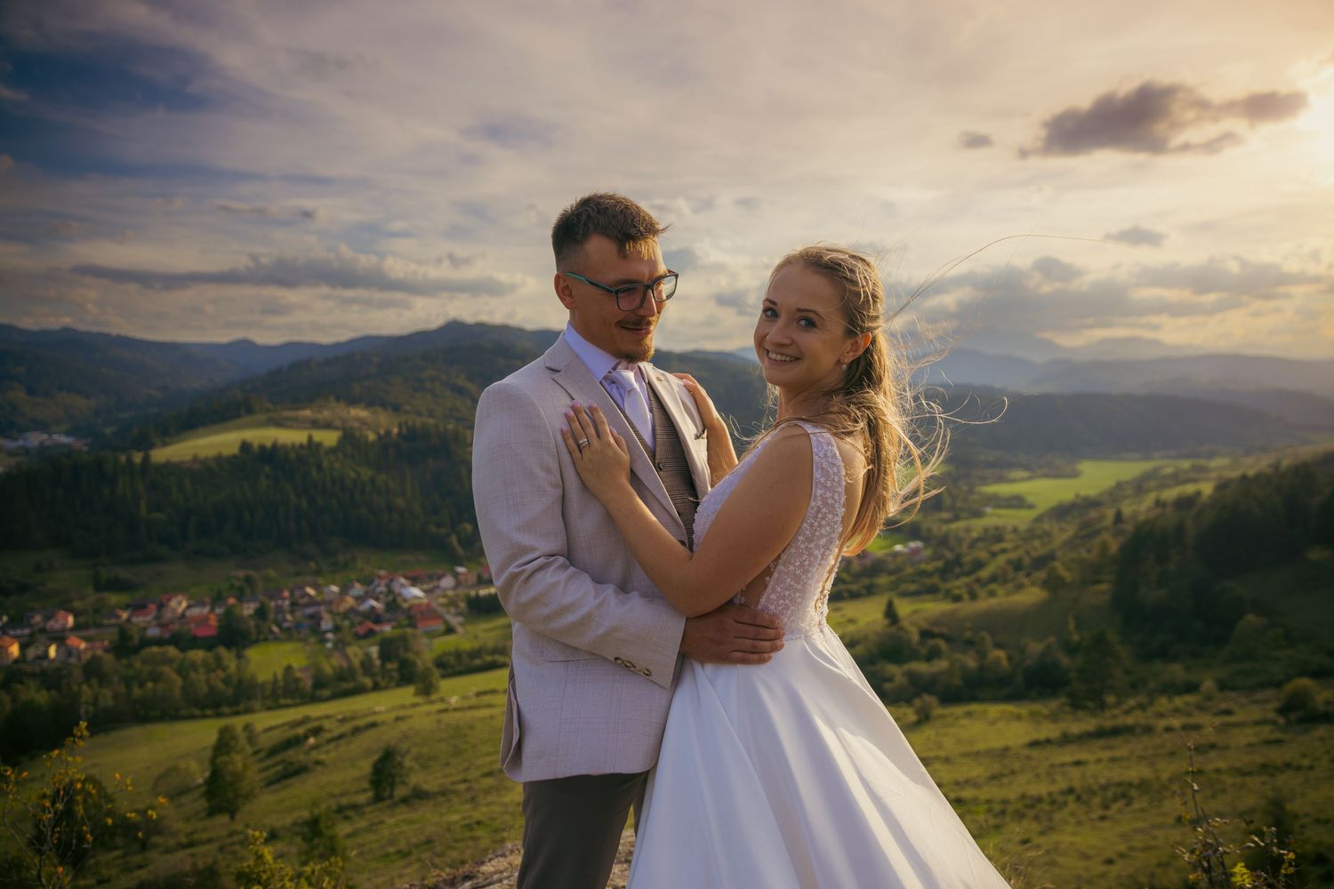 A couple shares an intimate moment against a dramatic mountain sunset backdrop.