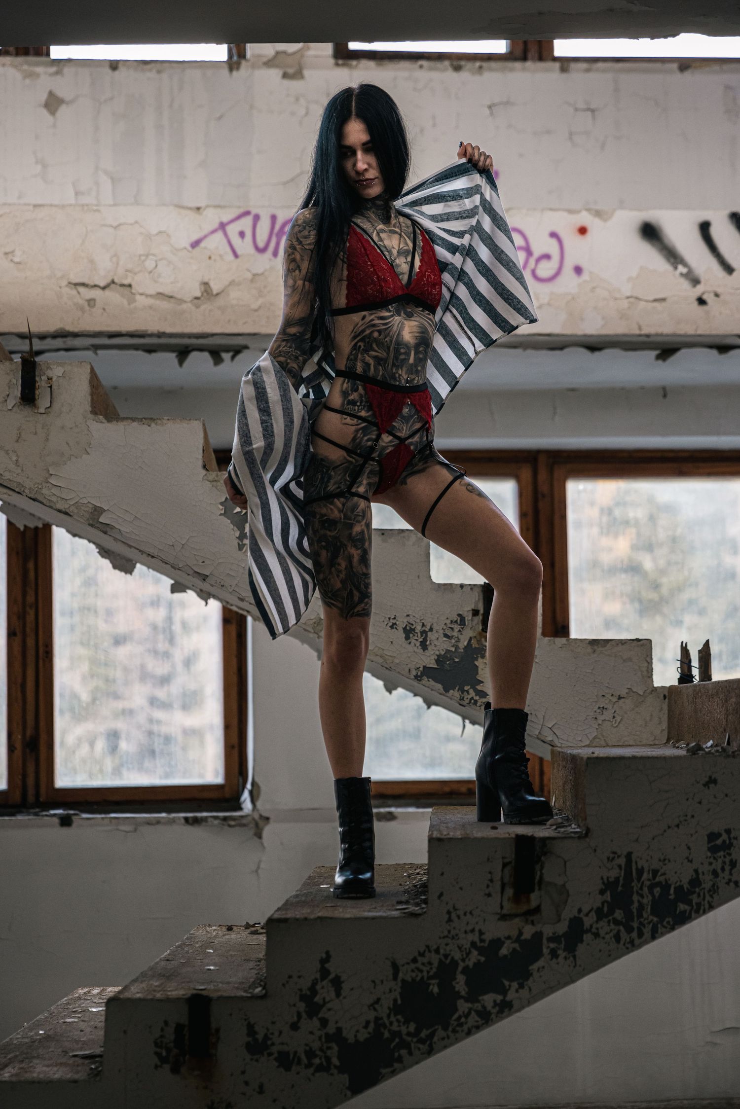 Dramatic poses on broken concrete stairs in an abandoned building with natural lighting.