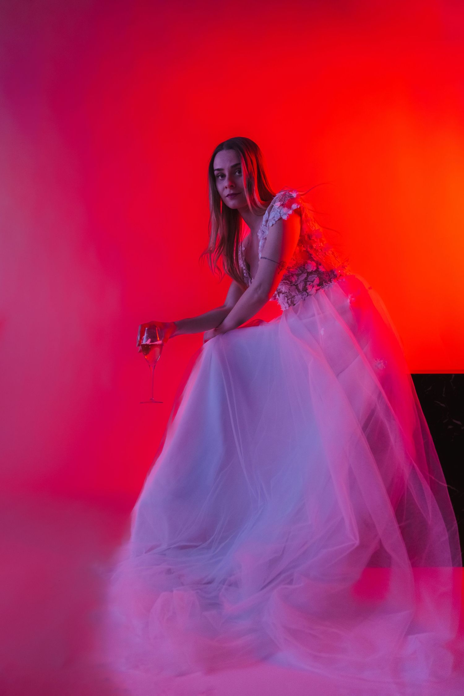 Artistic fashion photo series with ethereal white dress against dramatic red lighting and fog effects.
