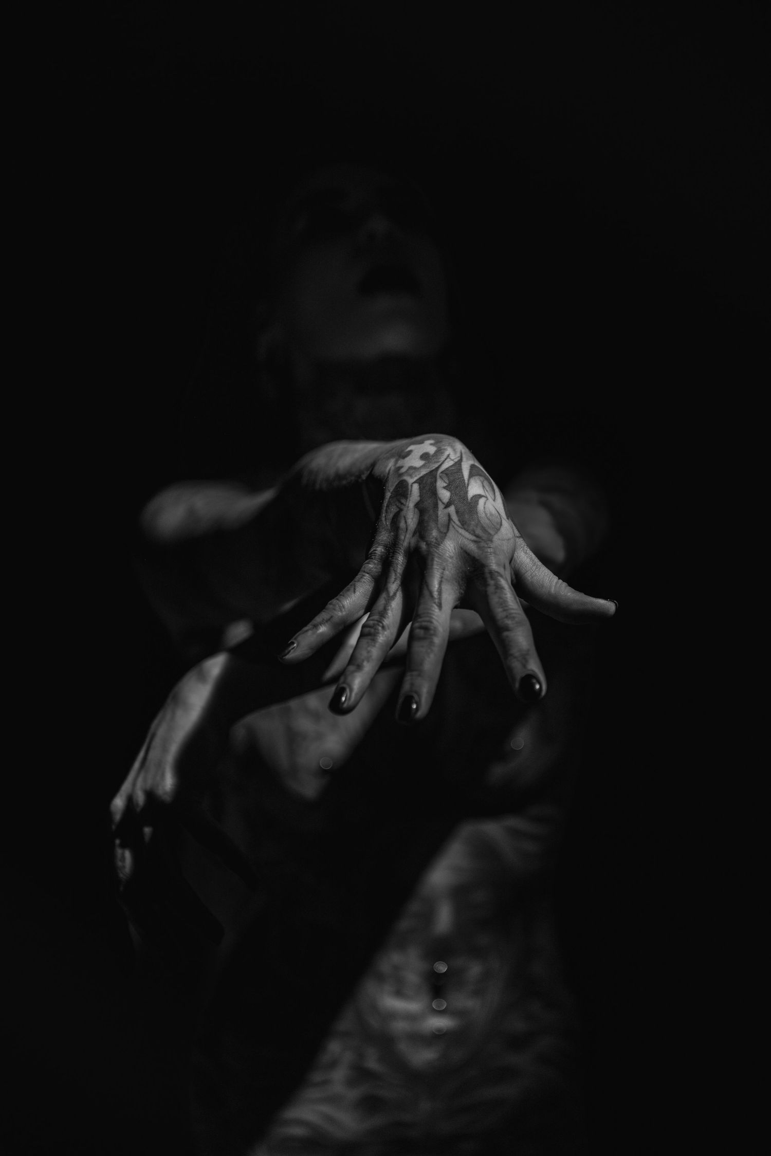 Artistic dark photo showing hands emerging from shadows with dramatic lighting.