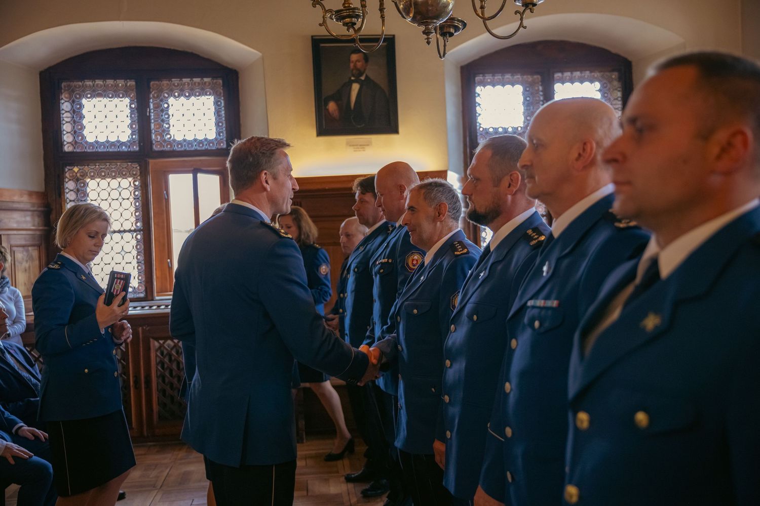Traditional meeting hall filled with uniformed personnel during an official ceremony.