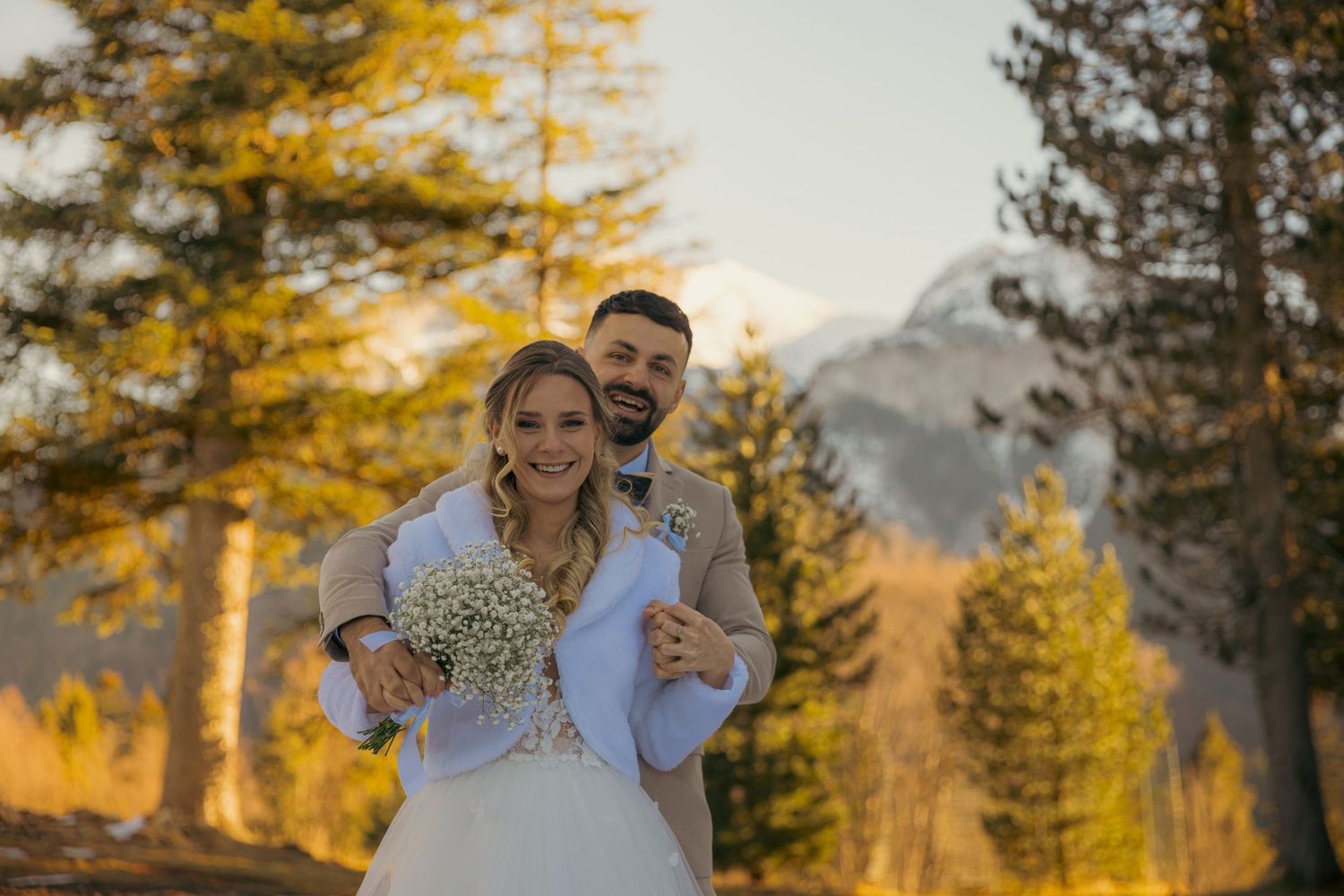 Newlyweds sharing intimate moment during golden hour with fall foliage in background.
