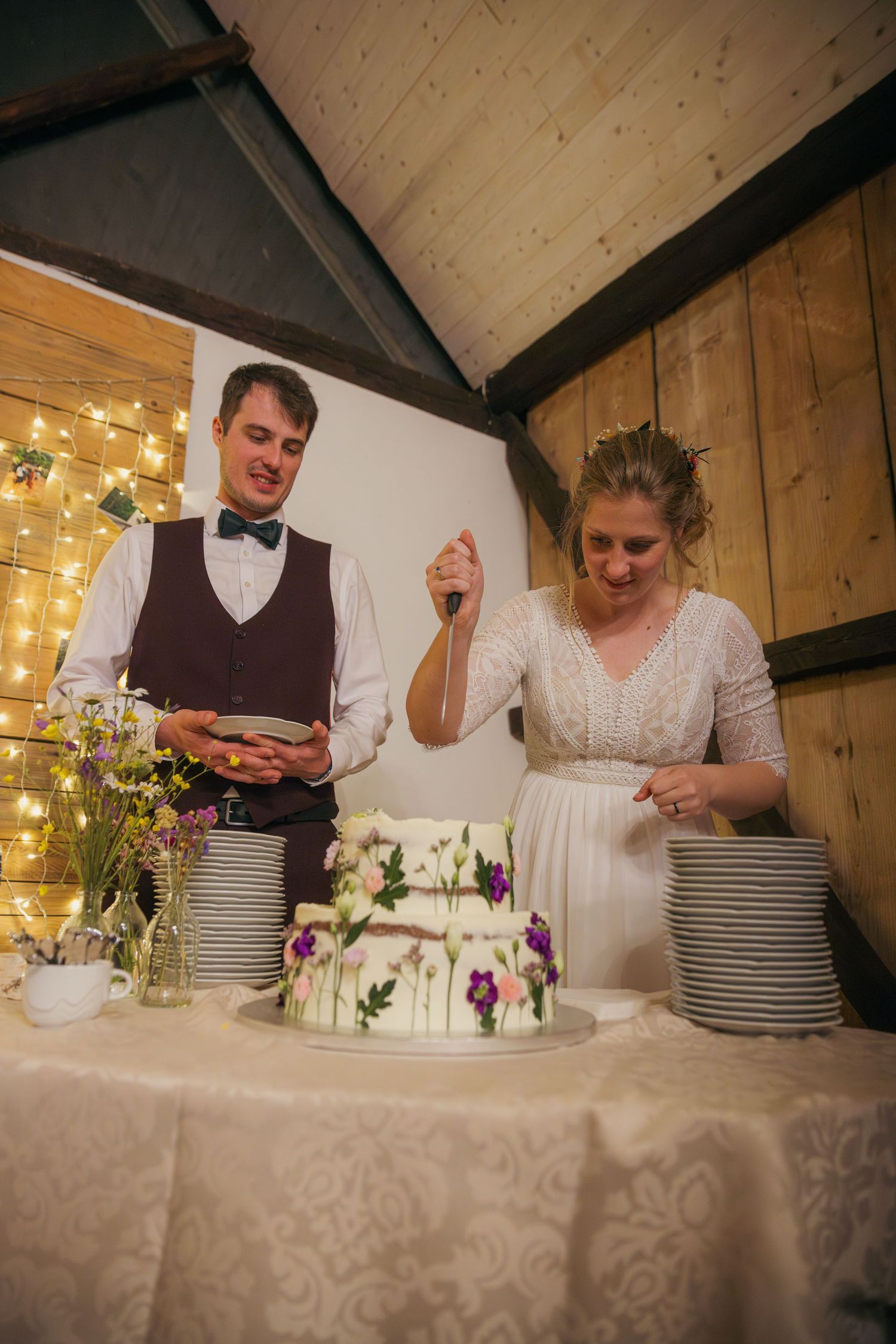 Wedding couple cutting their white tiered cake at the reception dessert table.
