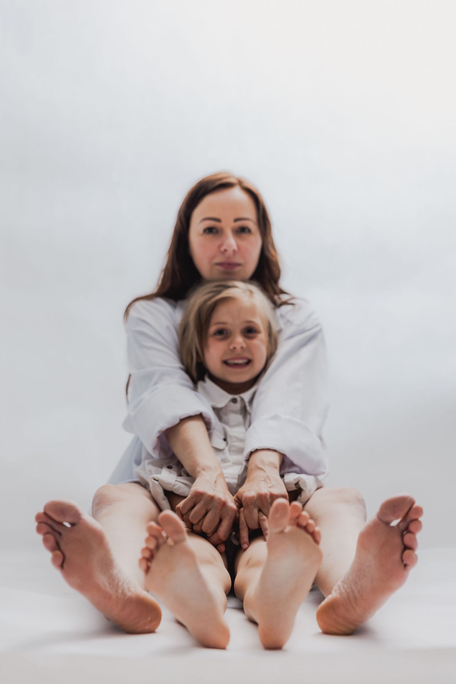 Two people in white shirts showing bare feet against white background.