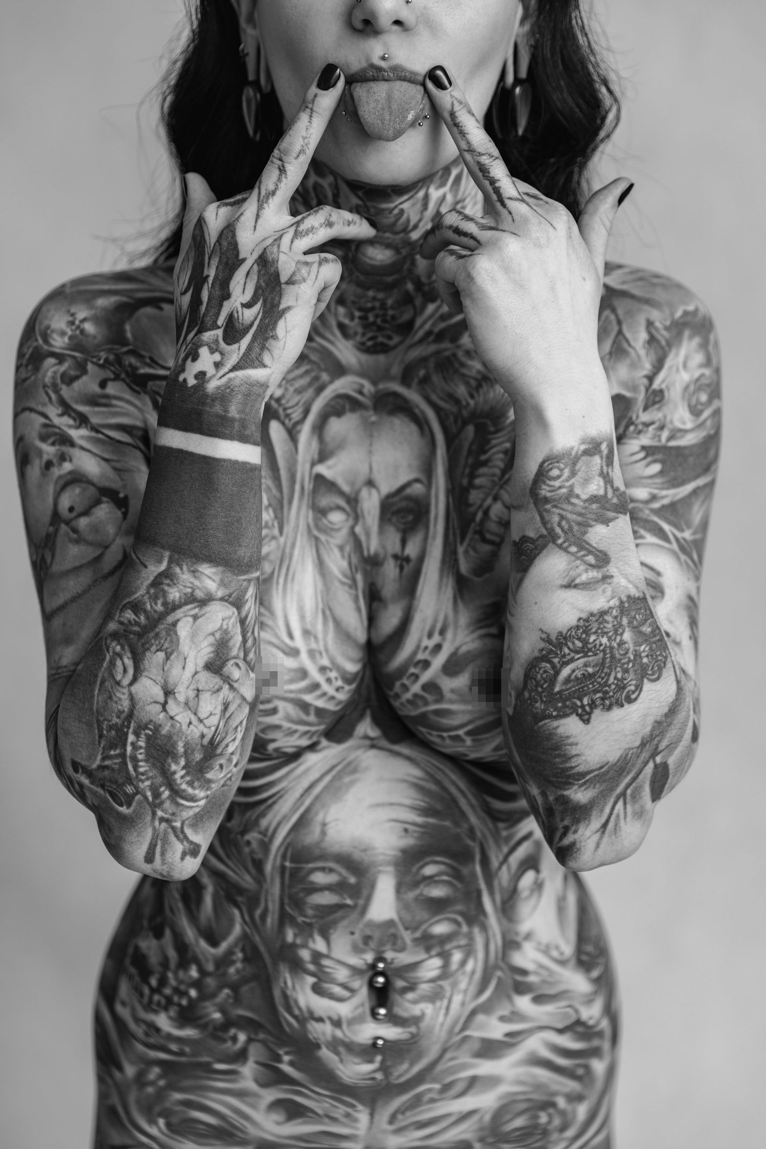 Black and white closeup of heavily tattooed torso with detailed sleeve artwork.