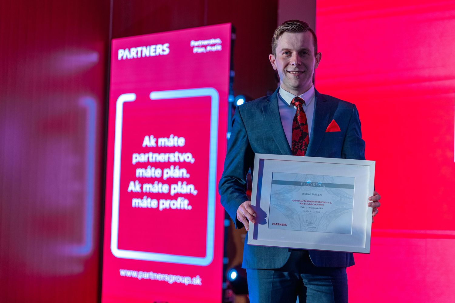 Business presentation with red backdrop showing award recipient holding certificate.
