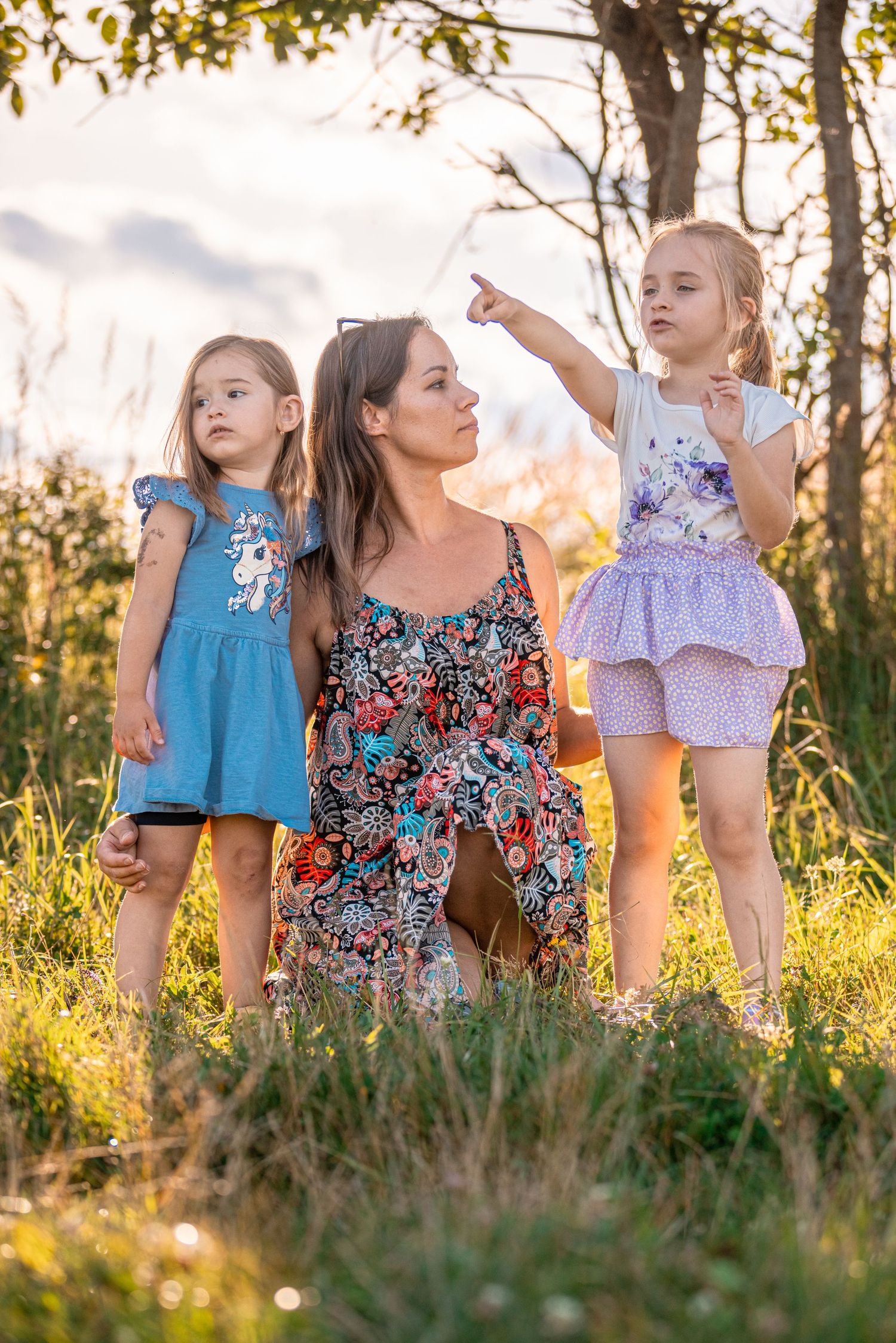 A group wearing colorful dresses explores a sunlit meadow at dusk.