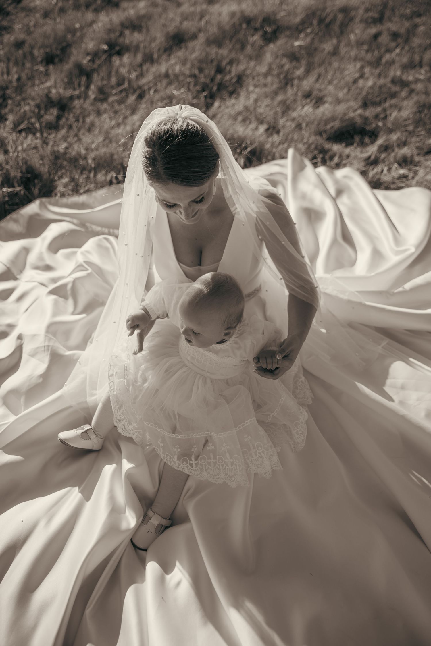 Close-up details of an ornate white wedding dress spread out on the ground.