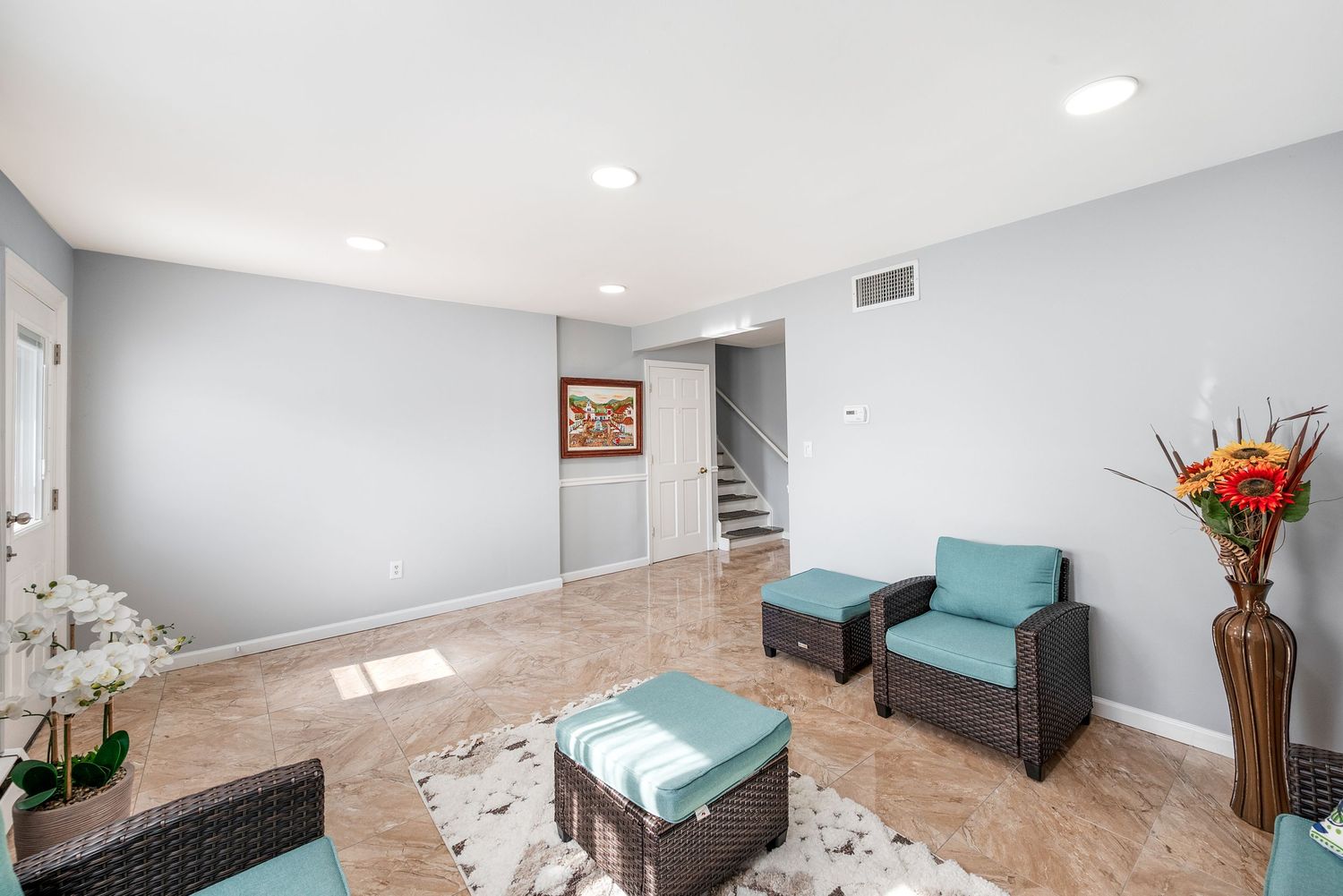 Large bright family room with grey walls featuring whicker and green patio furniture.