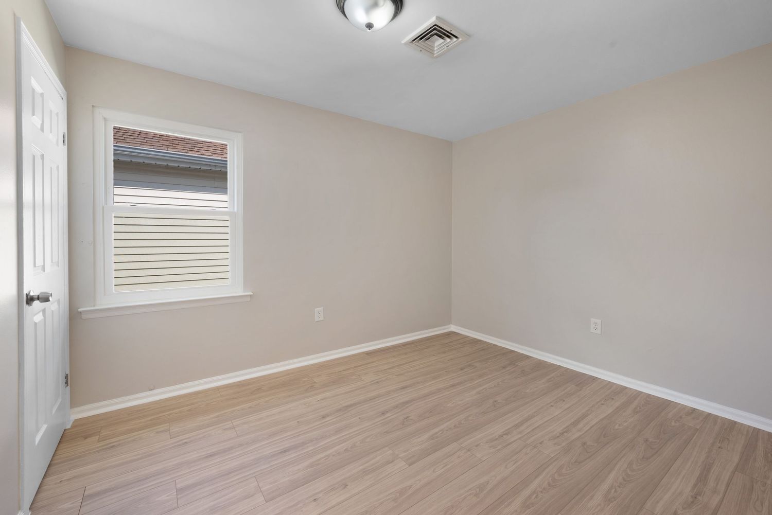 Small bedroom with window and hardwood floors.