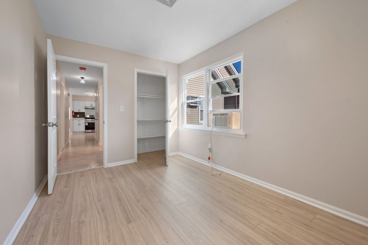Medium-sized bedroom with window, closet, light hard-wood floors.