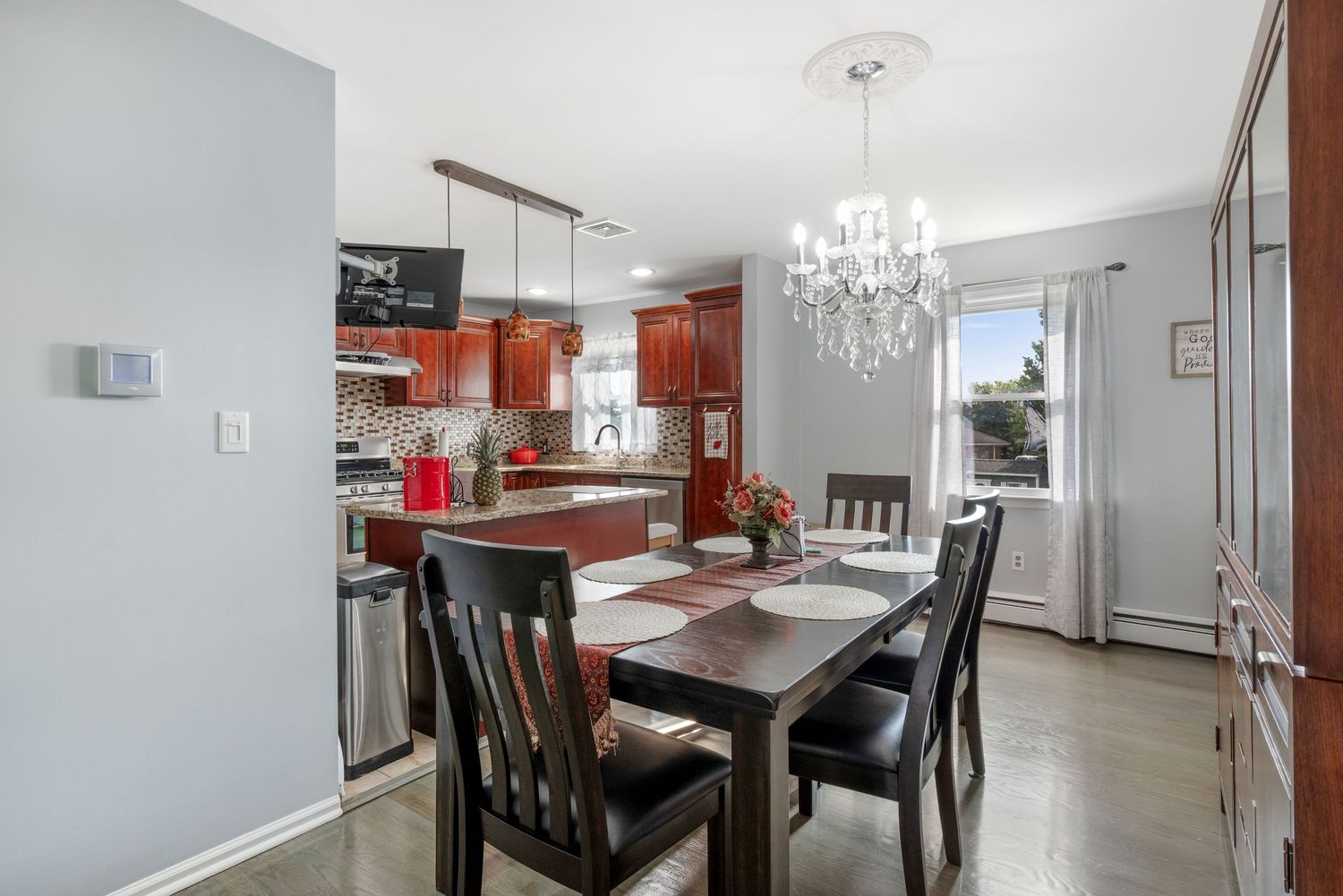 Dining room with grey walls and window featuring a beautiful chandelier and dark wood dining table and chairs.