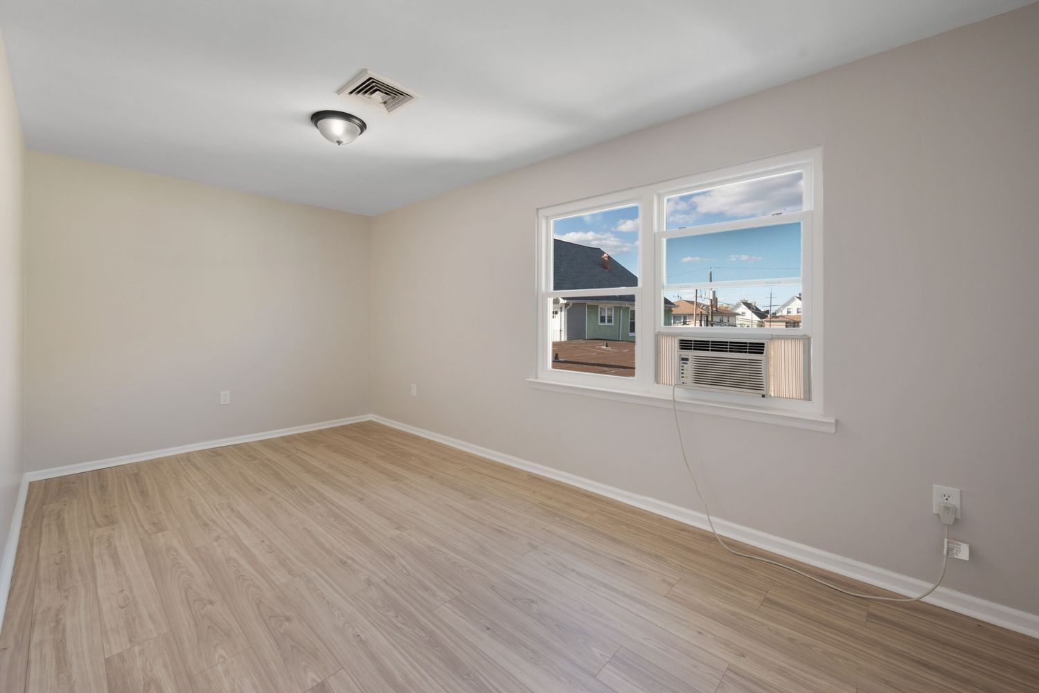 Large bedroom with windows and hardwood floors.