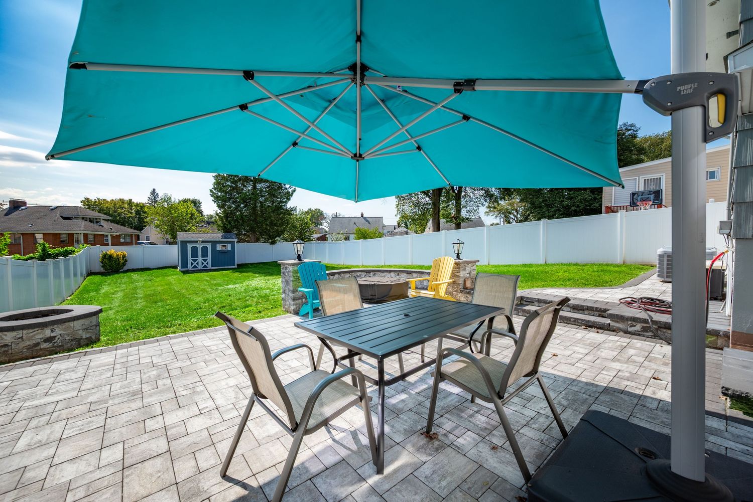 Backyard patio with large umbrella and patio furnature.