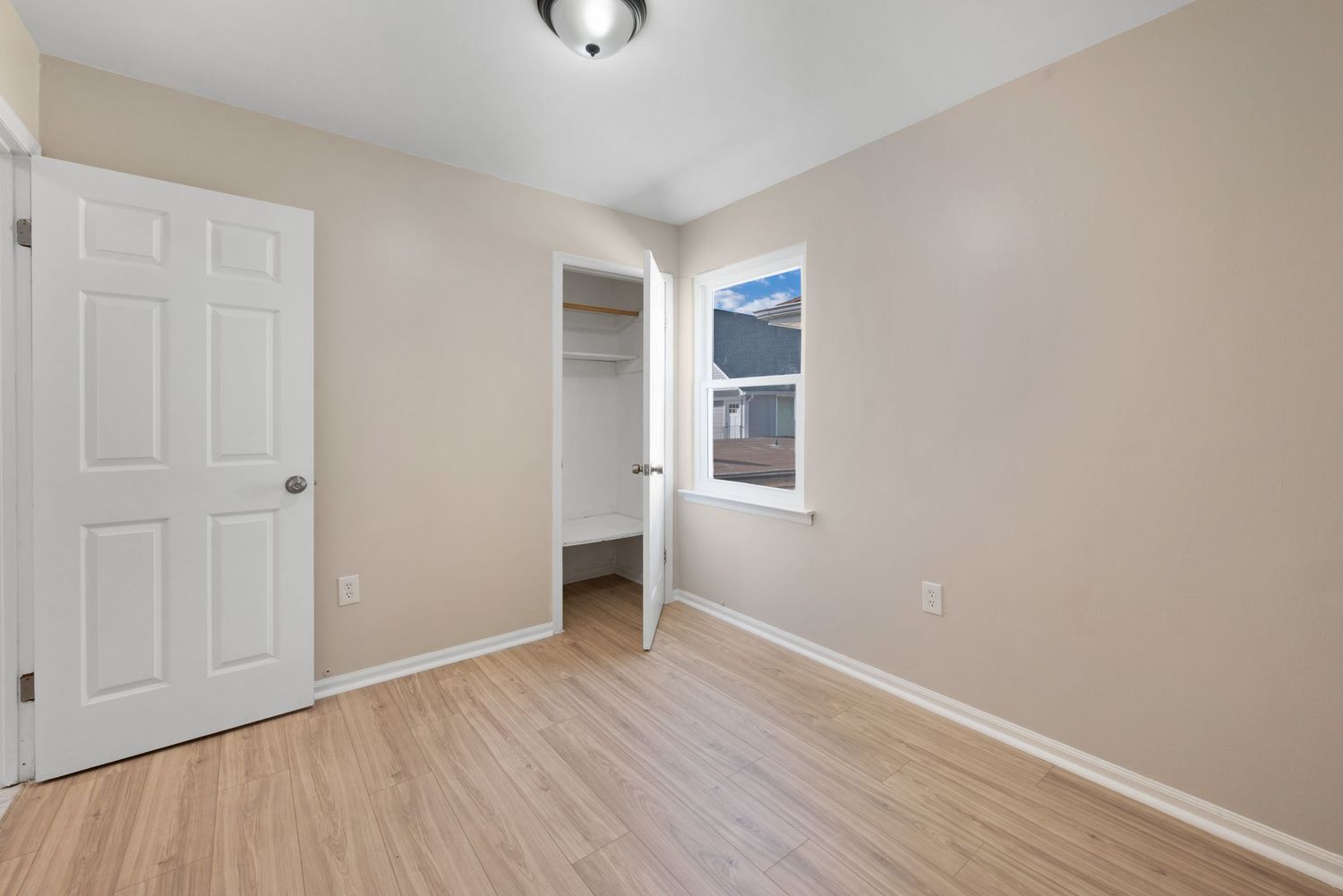 Small bedroom with closet, window, and hardwood floors.