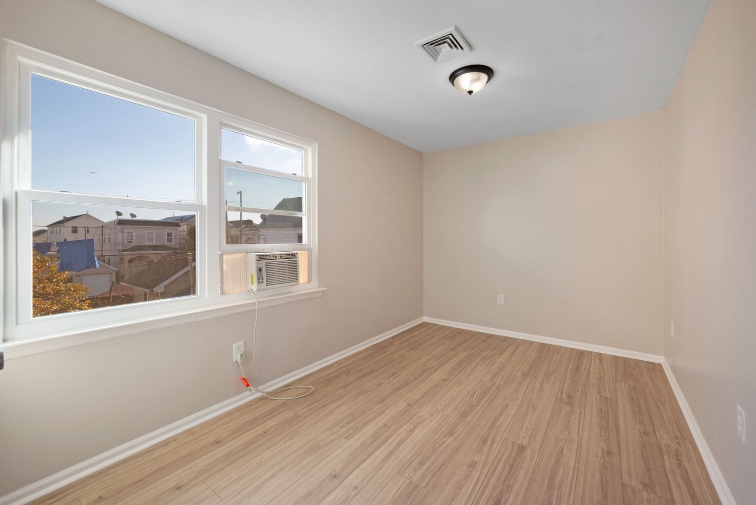 Bright Medium-sized bedroom with large window, light hard-wood floors.